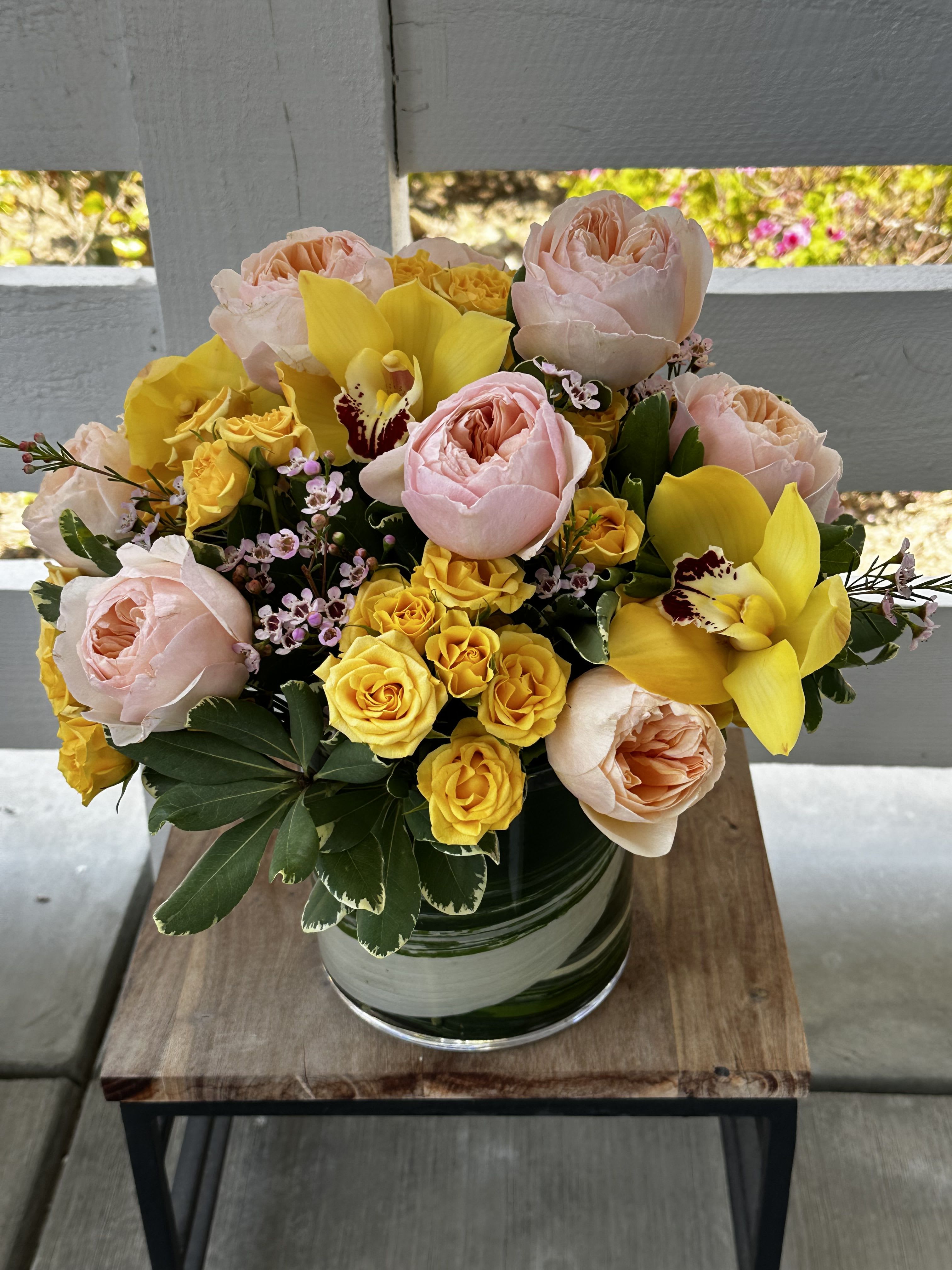 Bright Smiles - Garden roses, spray roses, orchids, wax flower and  seasonal greenery.