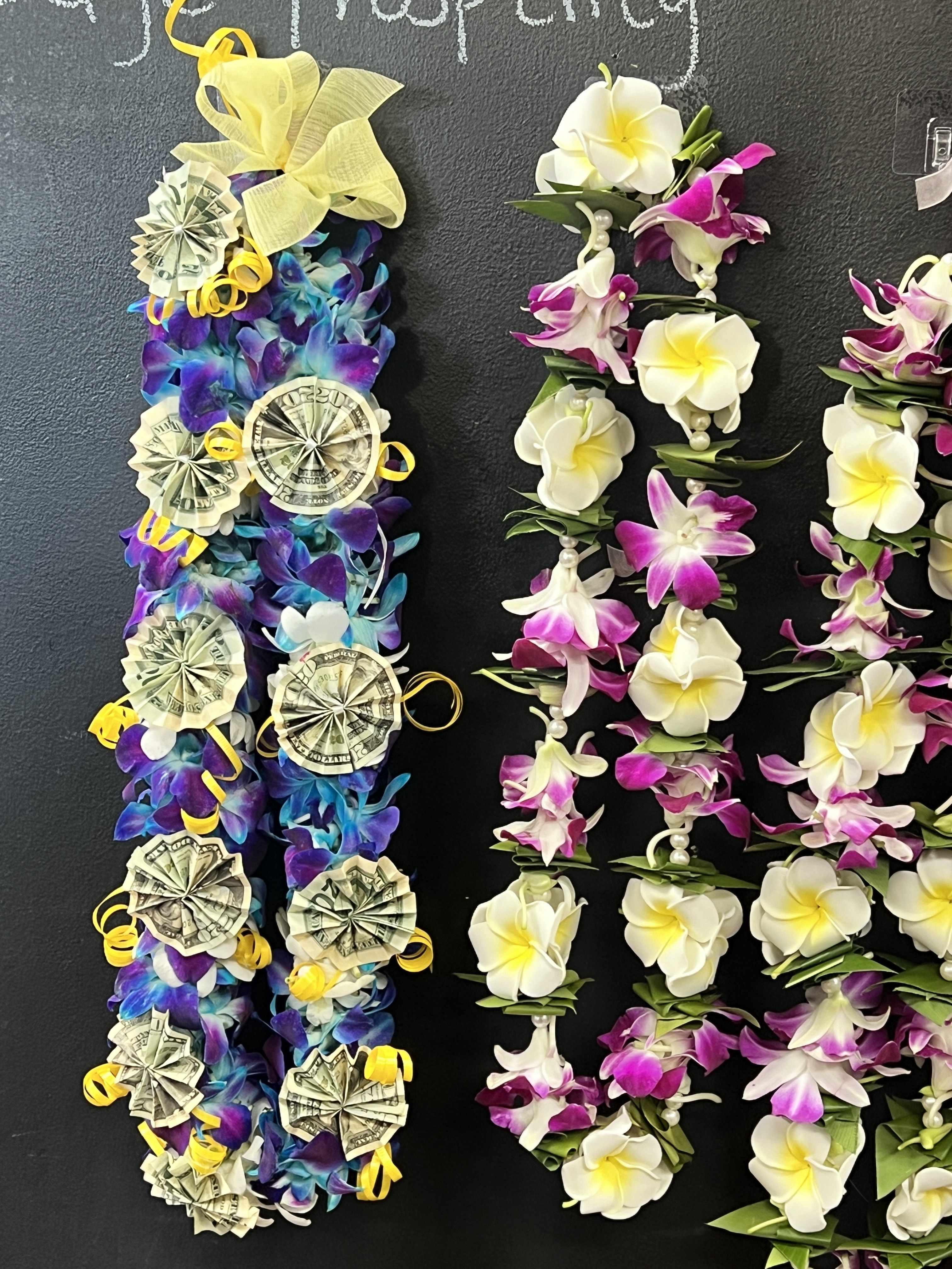 Lei-style floral garlands with white and purple flowers and money rosettes