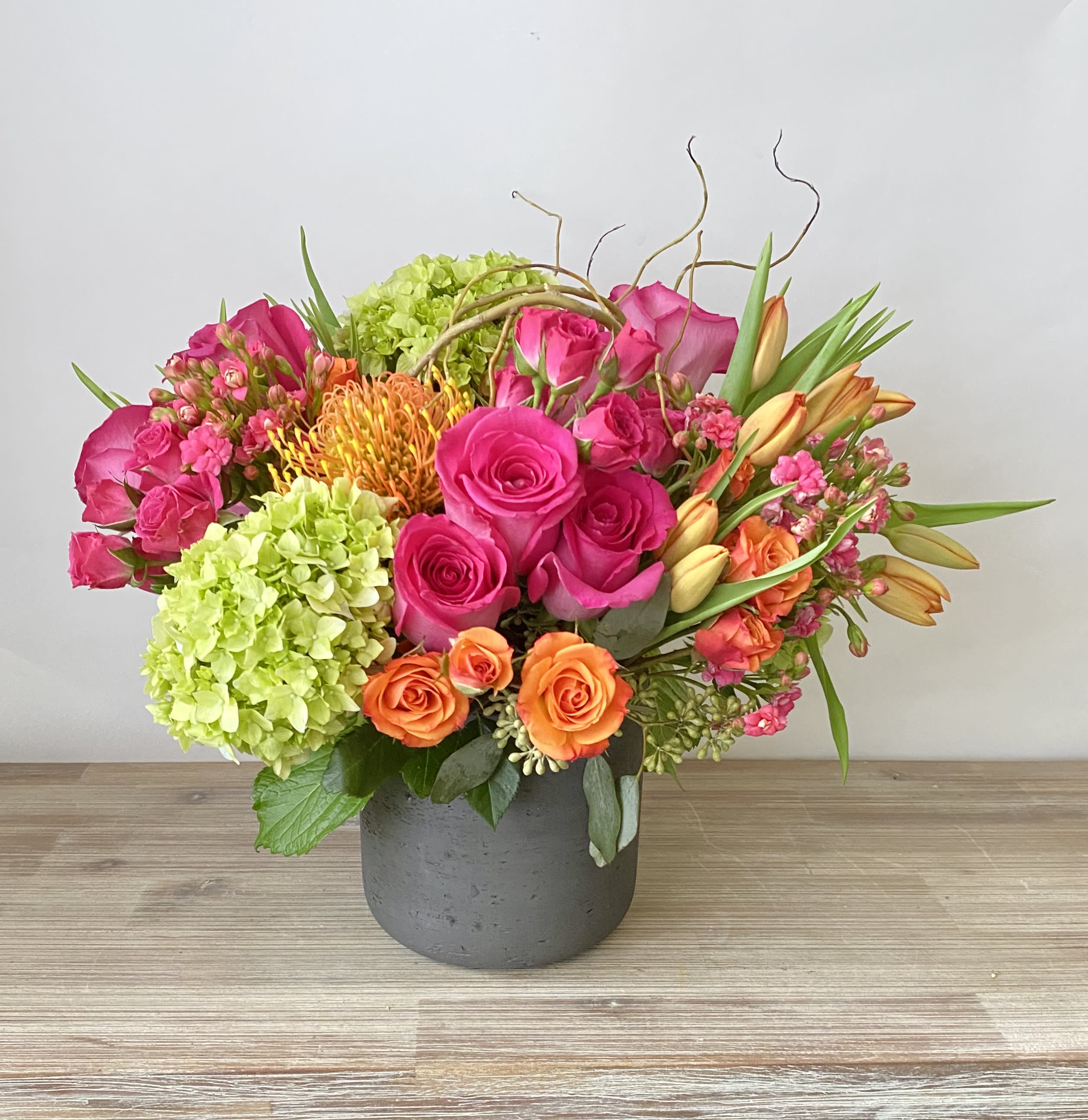 Bright mixed bouquet of pink and orange flowers in a gray vase