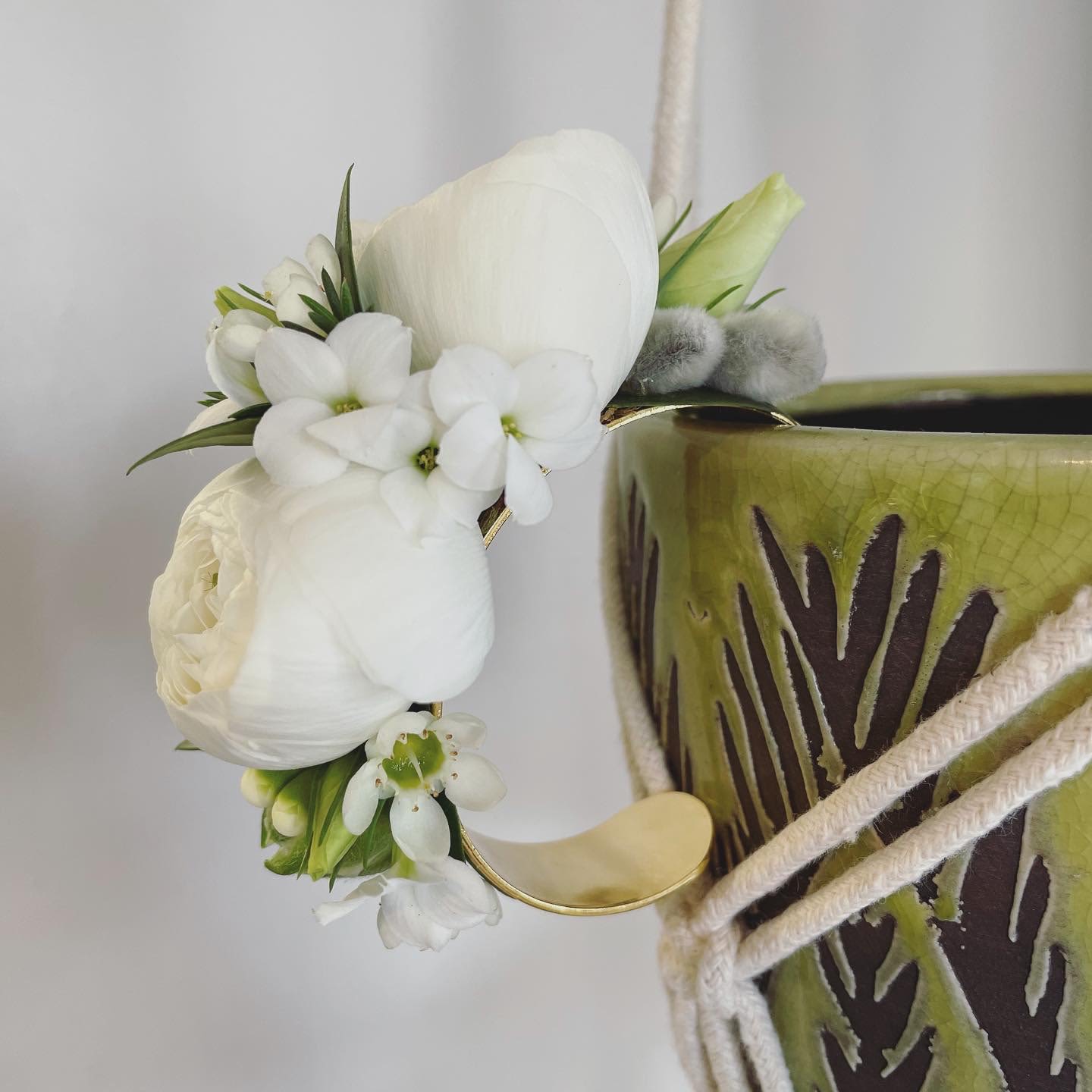 Ranunculus Corsage on a Gold Cuff -- Pick Up Only - Cuff corsage featuring ranunculus with bits of foliage and other filler flowers. Please note in the 'Special Instructions' box what color you'd like the focal flower to be and any other accent colors you'd like to see in the design. Please note that each corsage is botanical, unique and may differ from the image shown online. If no colors are noted in the 'Special Instructions' then we will use white flowers.  Please note that corsages and boutonnieres are non-refundable after being made. 