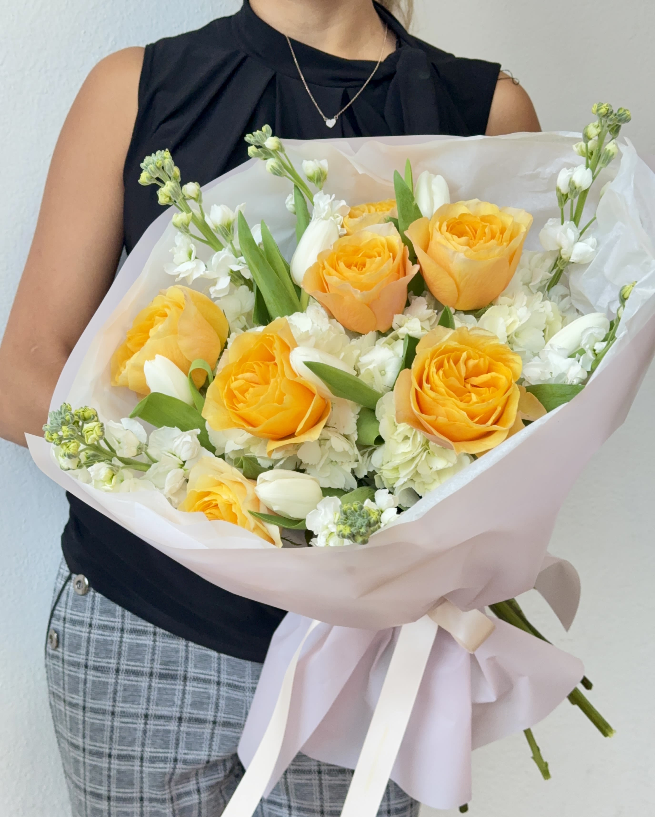 Bouquet of yellow roses and white flowers wrapped in pale pink paper