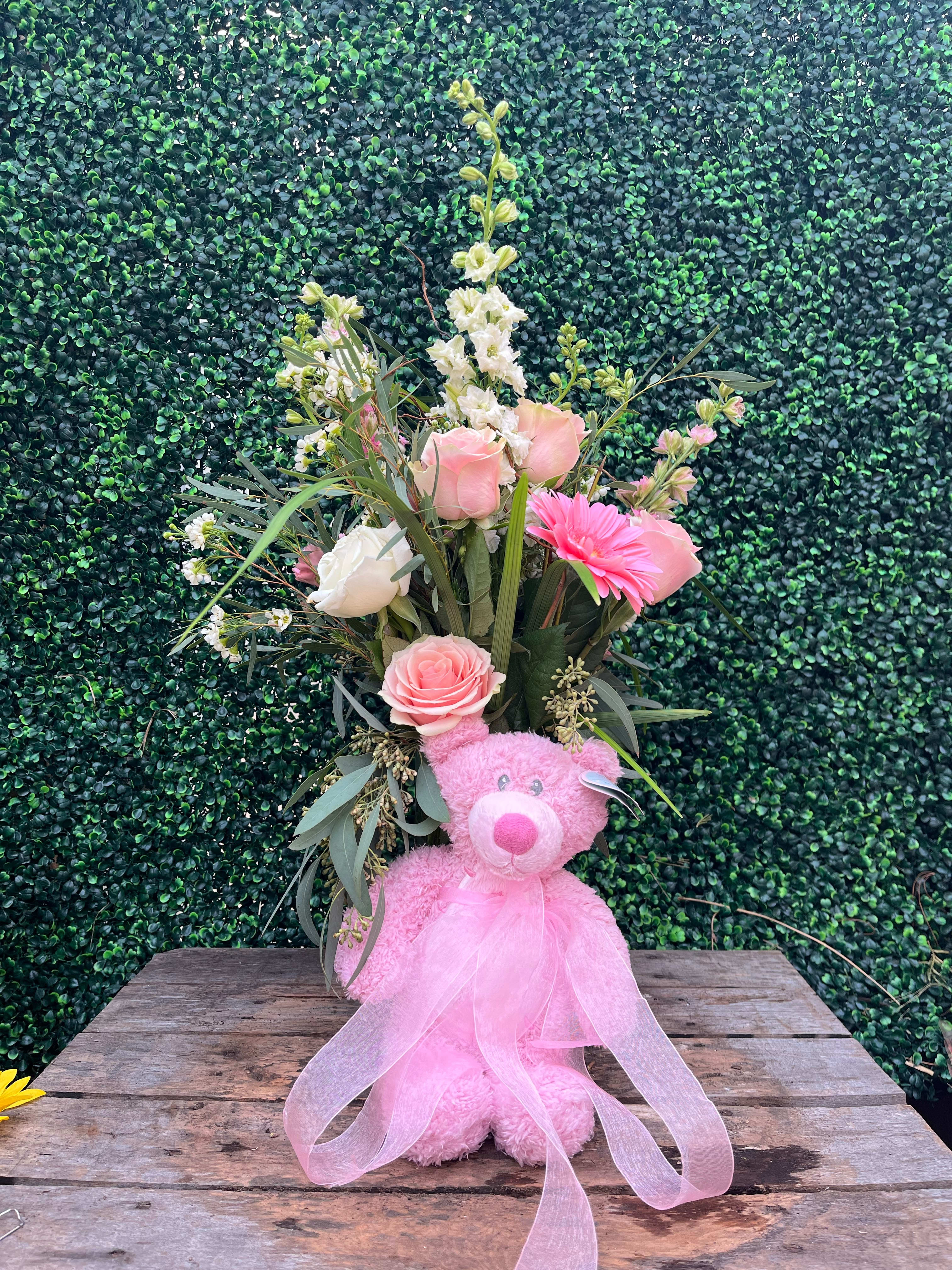 Pink teddy bear with a floral bouquet and sheer ribbon