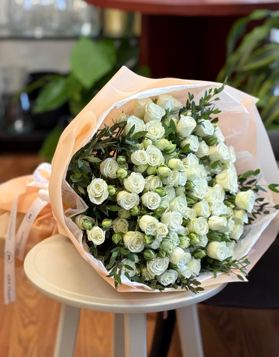 Bouquet of white spray roses wrapped in pale peach paper