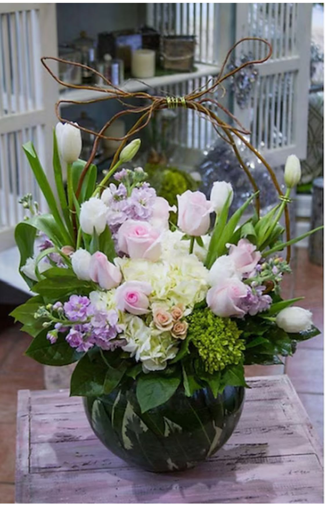Pink and white tulips with roses in a round glass vase