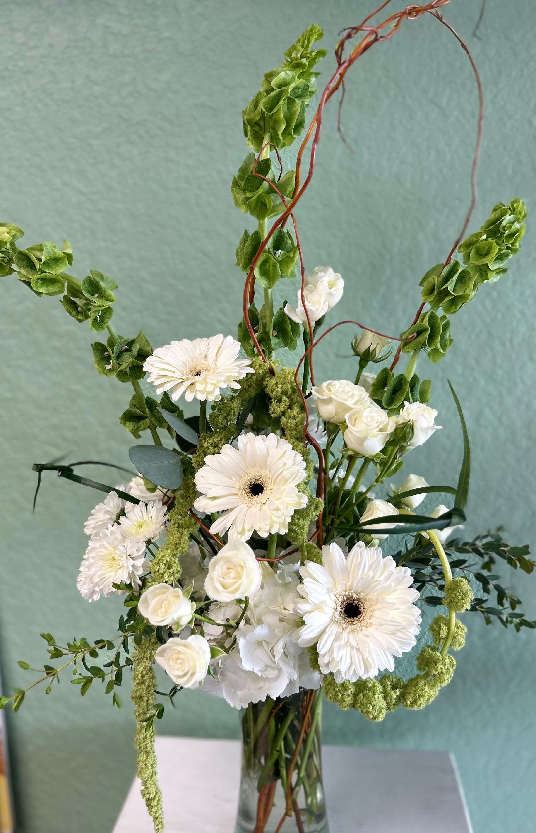 CFS107 - A mid height white and green arrangment of high end white &amp; green flowers such as hydrangeas, roses, bells of ireland, gerber daisies and other blooms. 
