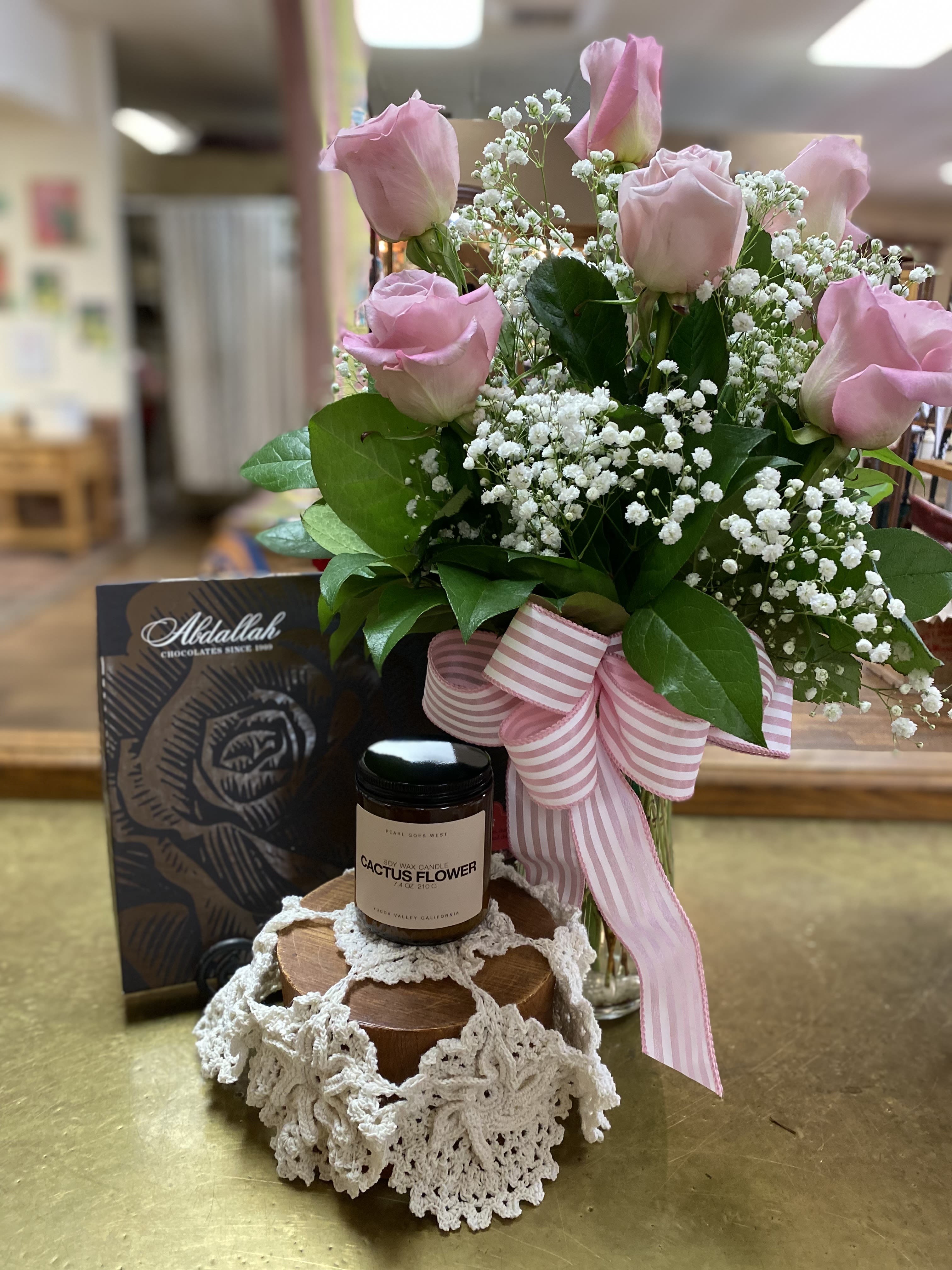 Pink roses with baby's breath in a glass vase, with chocolates and a candle