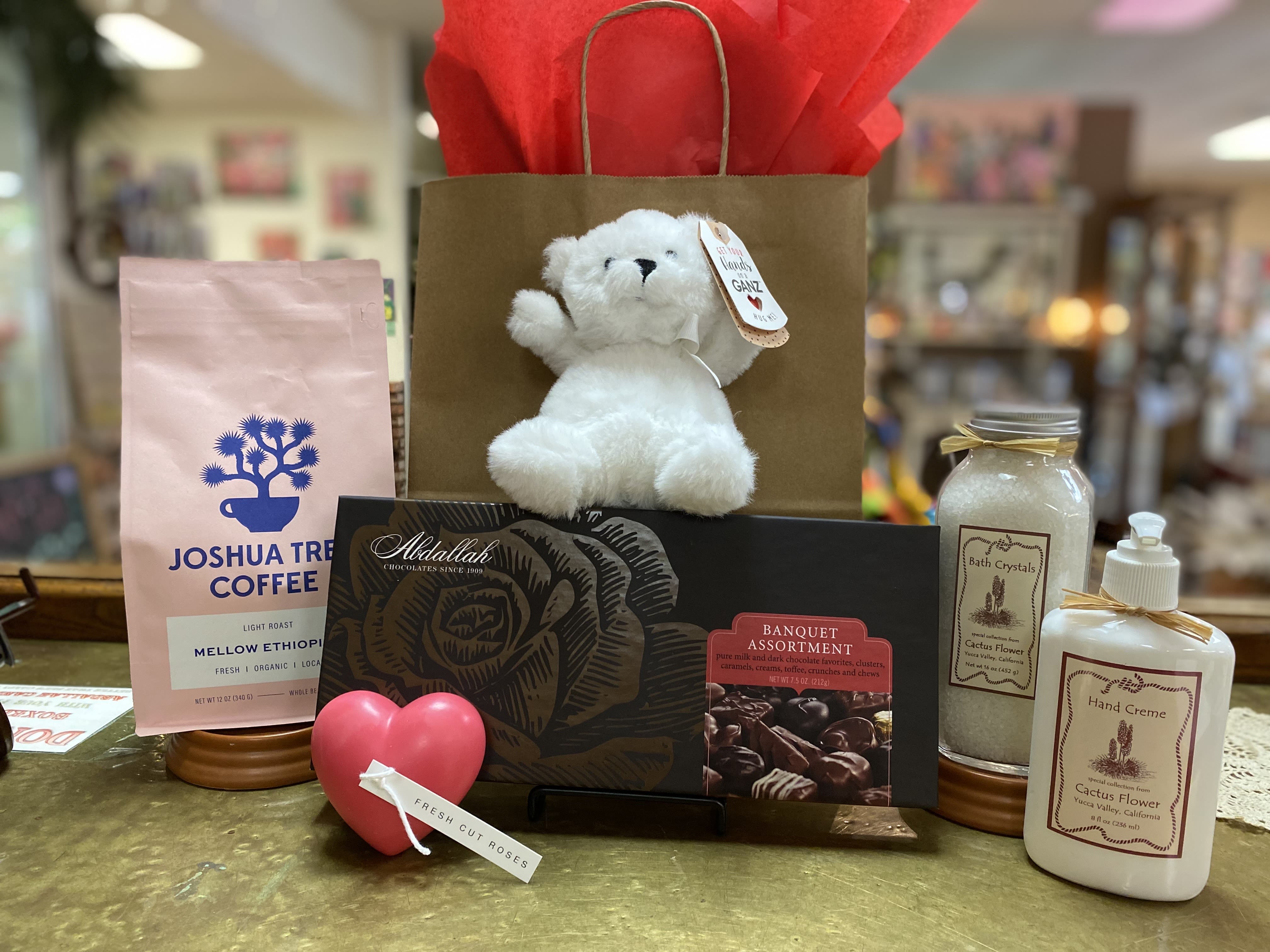 Gift basket with a teddy bear, chocolates, coffee, bath crystals, and hand cream