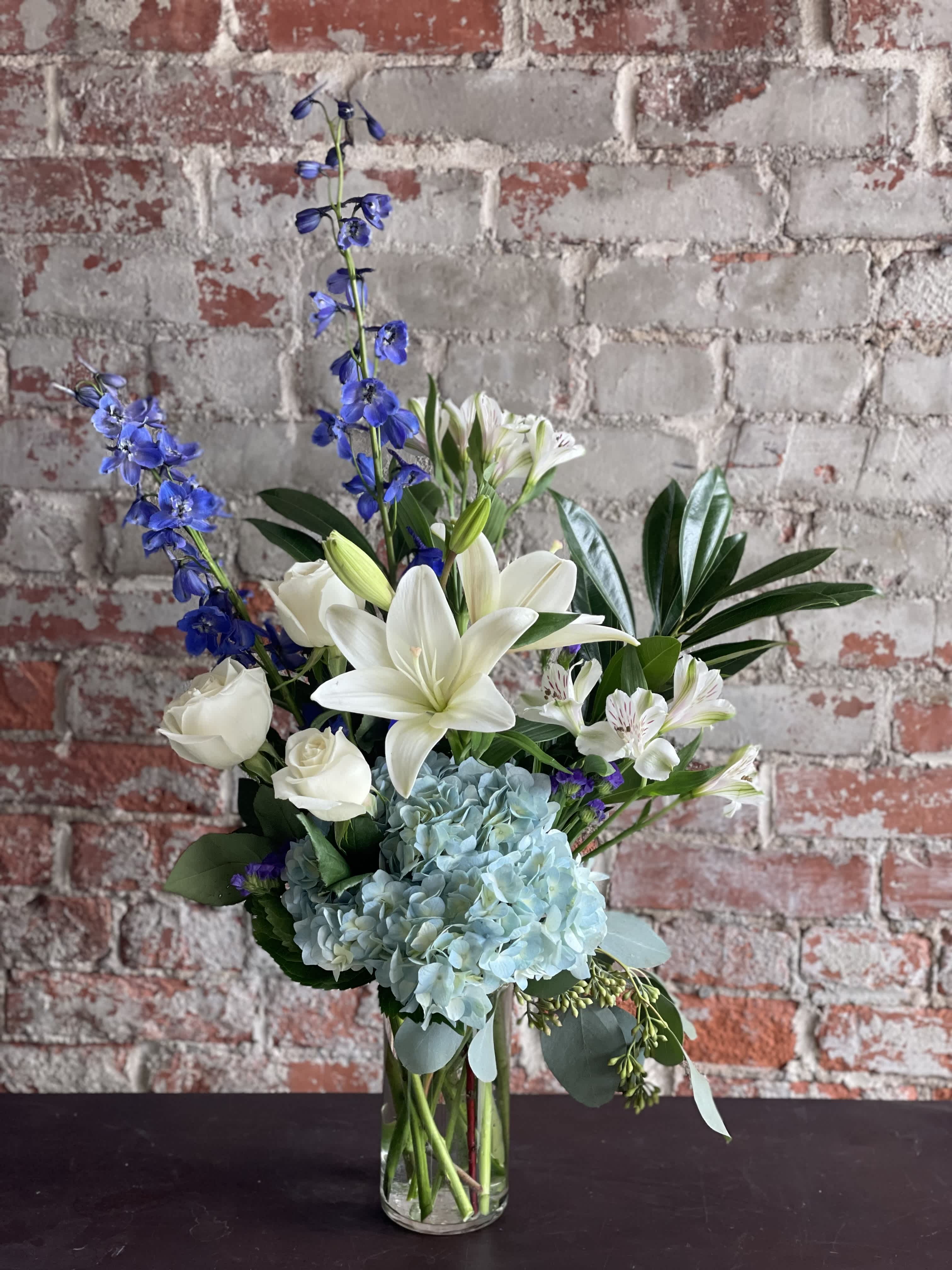 Blue and white floral arrangement in a clear glass vase