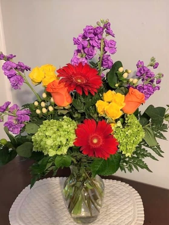 Colorful mixed bouquet in a clear glass vase with gerbera daisies and roses