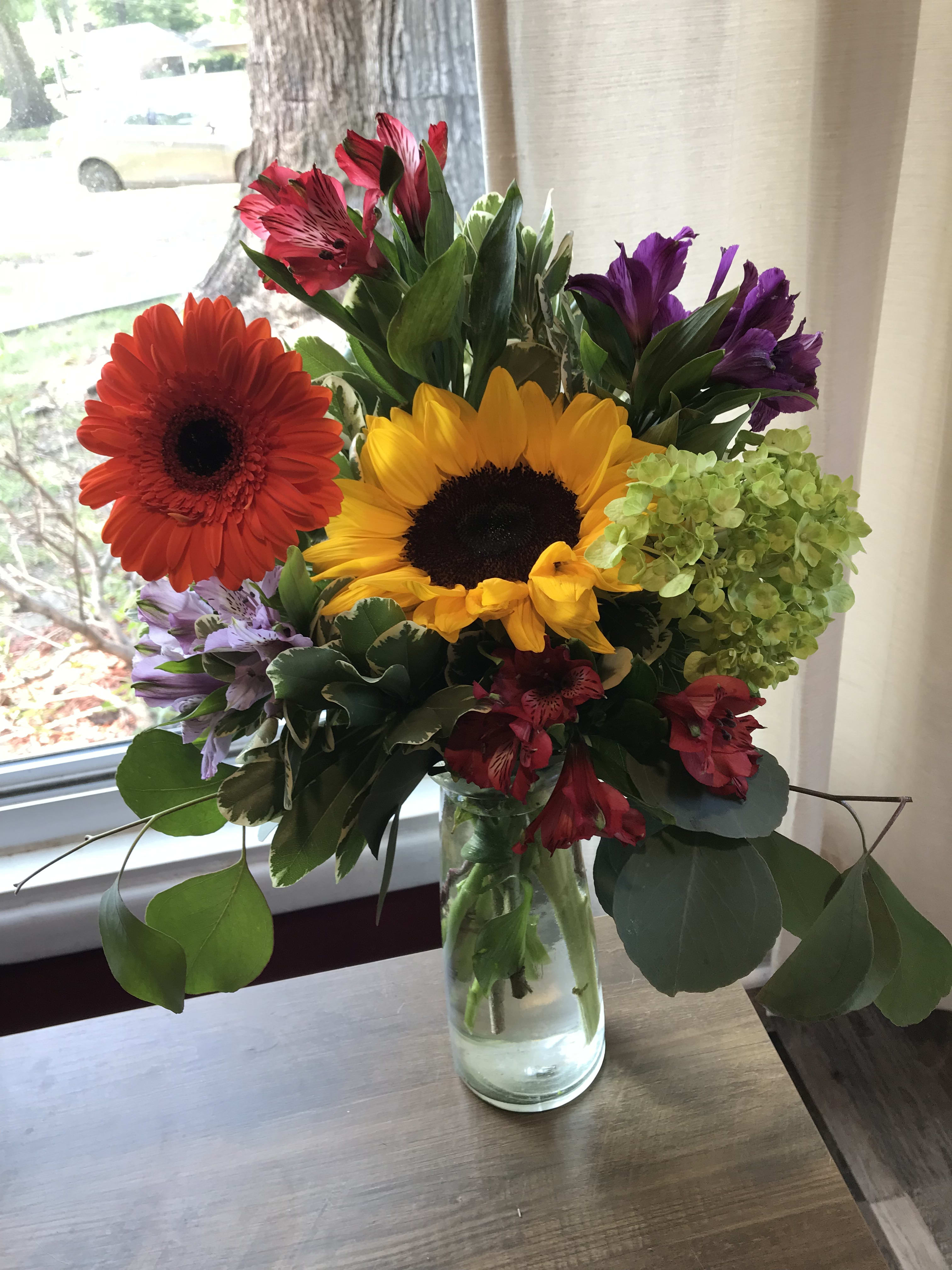 Mixed bouquet with sunflowers, gerbera daisies, and alstroemeria in a glass vase