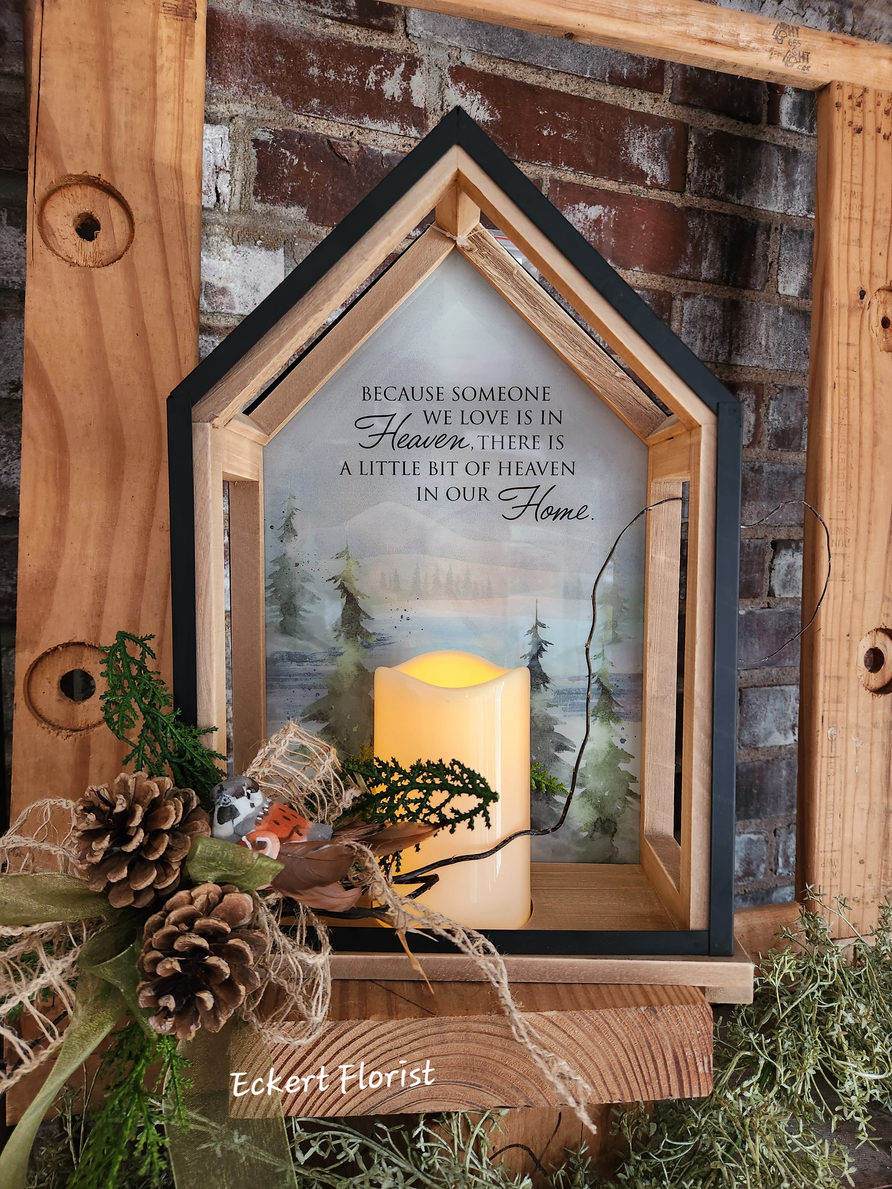 House-shaped memorial lantern with a candle and pinecone accent