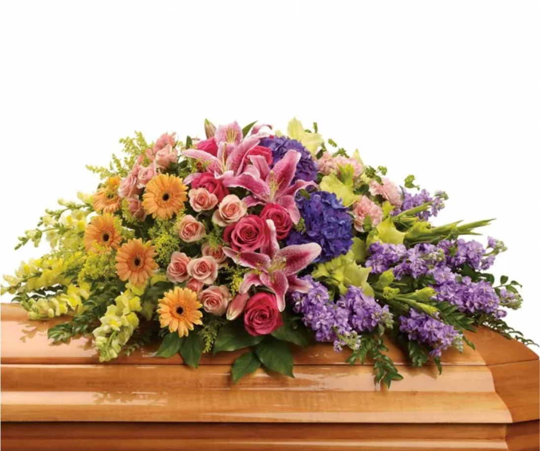 Colorful Garden Casket Spray - Embrace the vibrant beauty of life with our exquisite casket spray adorned with luxurious Purple Hydrangea as its centerpiece. Radiant Hot Pink Roses and delicate Peach Spray Roses intertwine, symbolizing love and admiration, while the soft petals of Pink Stargazer Lilies exude elegance and grace. Miniature Peach Gerberas add a touch of warmth and affection, complemented by the tall, regal stems of Green Gladioli. Pink Carnations and Yellow Snapdragons offer a gentle reminder of cherished memories, while lush Floral Greenery provides a verdant backdrop, symbolizing eternal love and remembrance. This opulent arrangement serves as a heartfelt tribute, celebrating a life well-lived and dearly cherished.  Includes: • Purple Hydrangea • Hot Pink Roses • Peach Spray Roses • Pink Stargazer Lilies • Miniature Peach Gerberas • Green Gladioli • Pink Carnations • Yellow Snapdragon