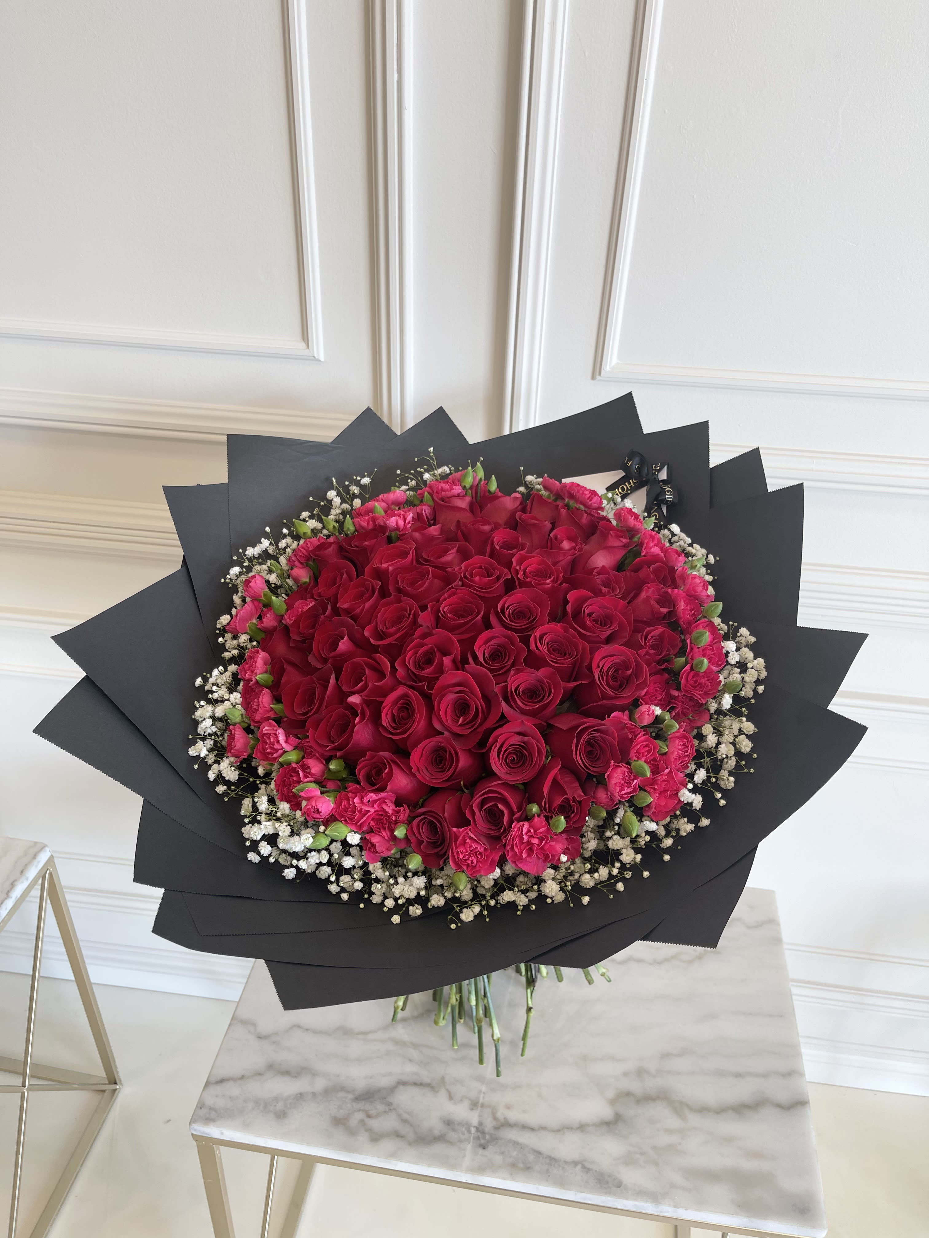 Large bouquet of red roses with pink carnations and white baby's breath in black wrap