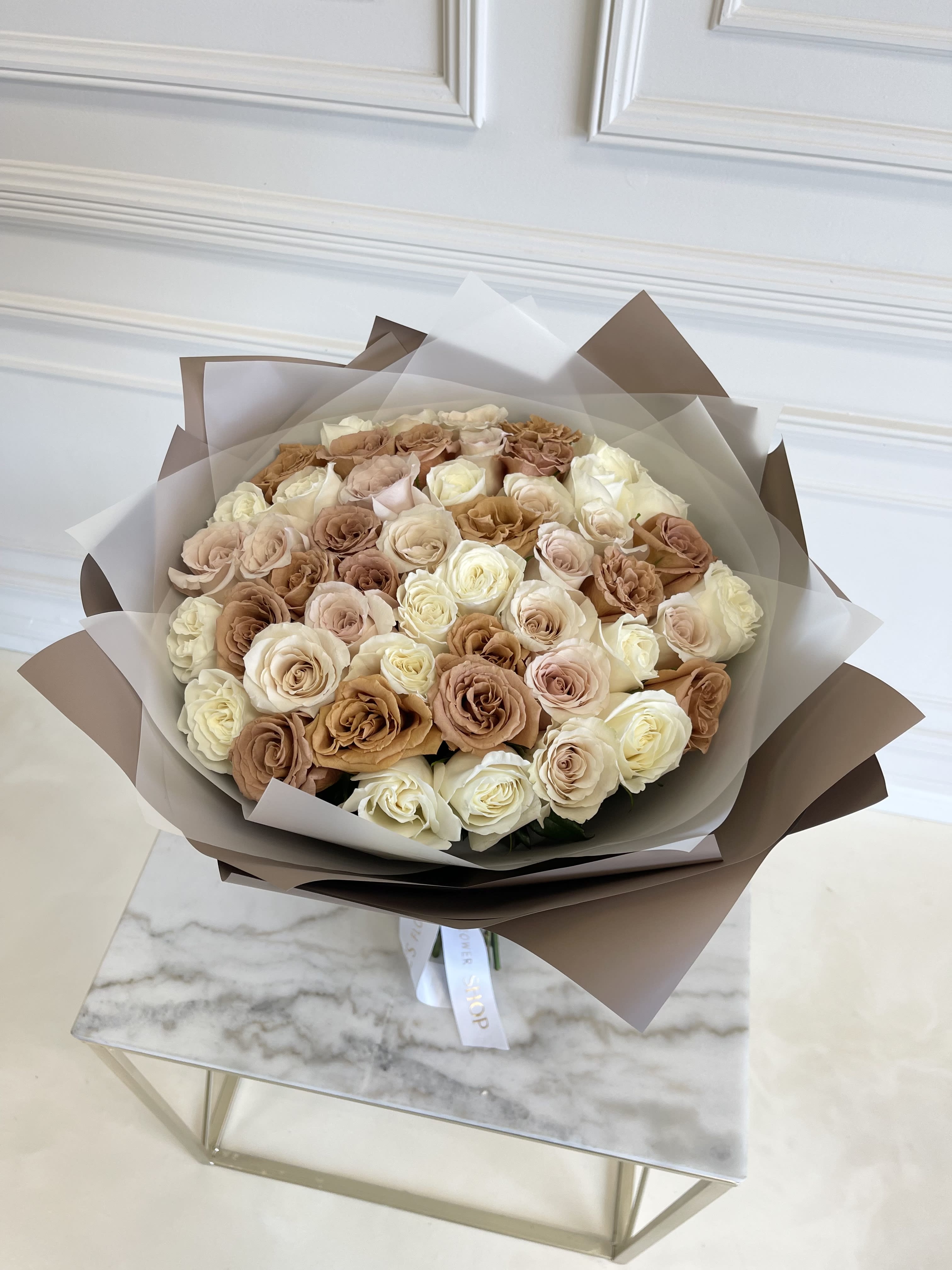 Bouquet of cream and blush roses wrapped in brown and white paper
