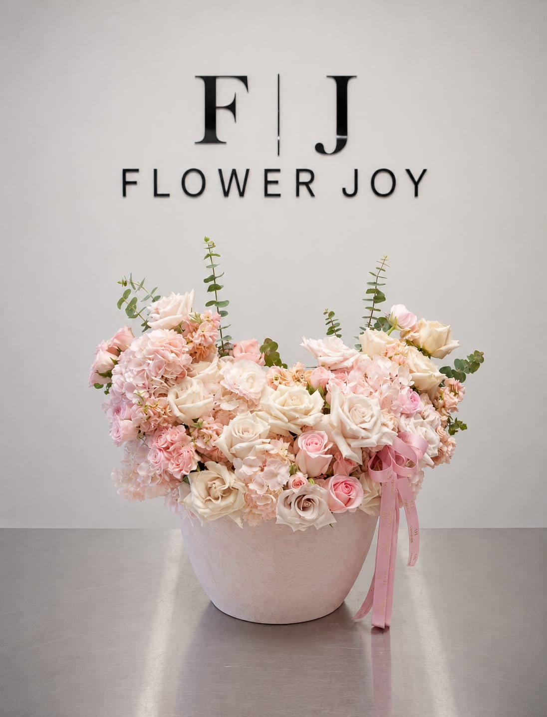 Blush Garden Harmony - A graceful arrangement of ivory and blush roses, soft hydrangeas, delicate seasonal blooms, and fresh eucalyptus, beautifully presented in a textured blush vase. Romantic, elegant, and timeless, perfect for birthdays, anniversaries, engagements, or heartfelt celebrations.