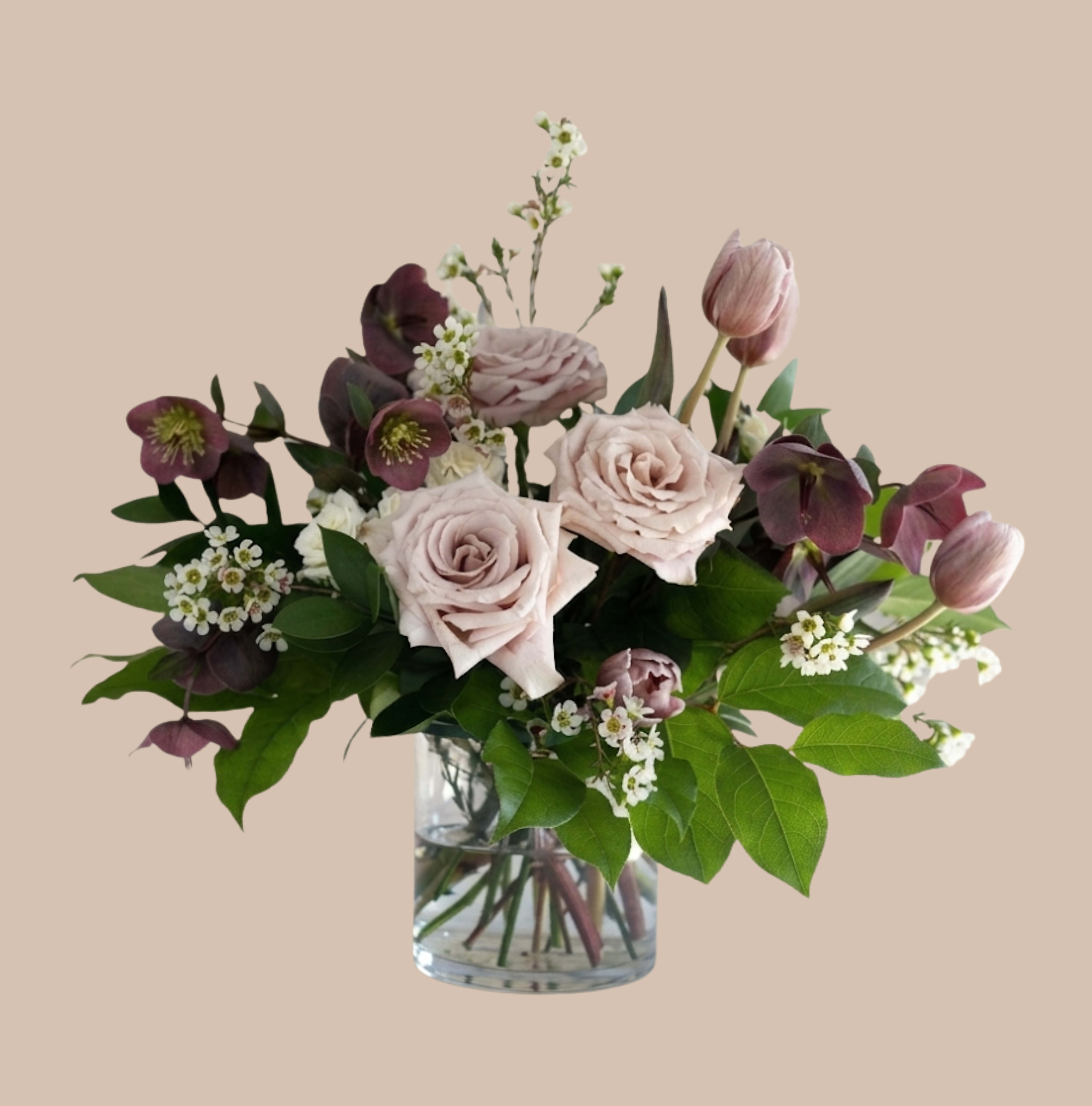 Velvet &amp; Vine - Pale blush roses paired with deep plum blooms and soft pink tulips create a romantic, garden-inspired arrangement perfect as a birthday bouquet or a gentle "thinking of you" gift. The color story of pink, purple, white, and green reads refined and comforting - the kind of bouquet that helps someone feel seen and celebrated whether they're recovering, receiving thanks, or marking a small victory.  This full, slightly asymmetrical design is arranged in a clear glass vase with taller stems rising above a lush cluster of blooms and broad green foliage fanning at the base. Small white filler flowers add delicate texture between the roses, tulips, and darker plum blossoms, giving the arrangement a layered, tactile look that feels both classic and contemporary.  Ideal for Get Well wishes, Thank You gestures, or a thoughtful Congratulations, this piece suits everyday gifting as well as special moments. The vase-arranged format arrives ready to display; refresh water and trim stems every few days to keep the flowers looking their best.