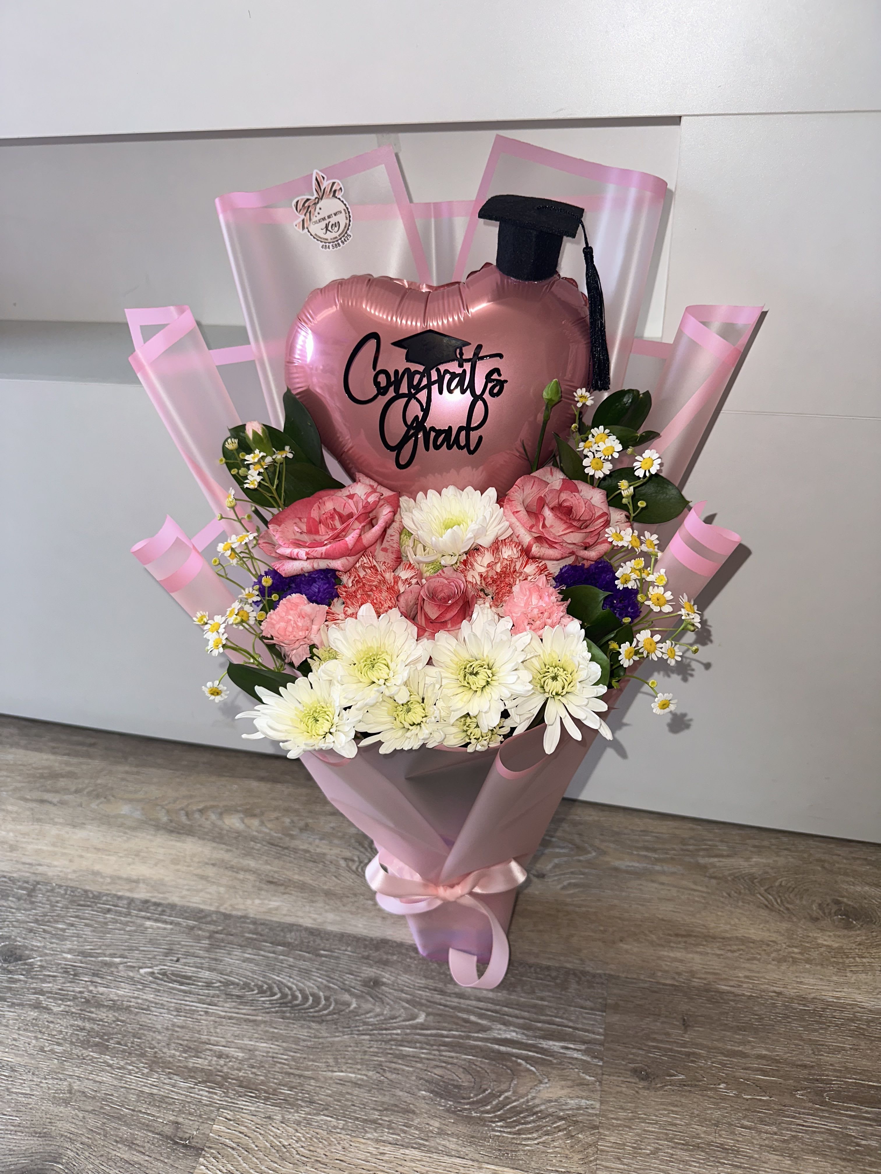 Graduation detail with balloon, graduation cap, and natural flowers - Graduation detail with balloon, graduation cap, and natural flowers