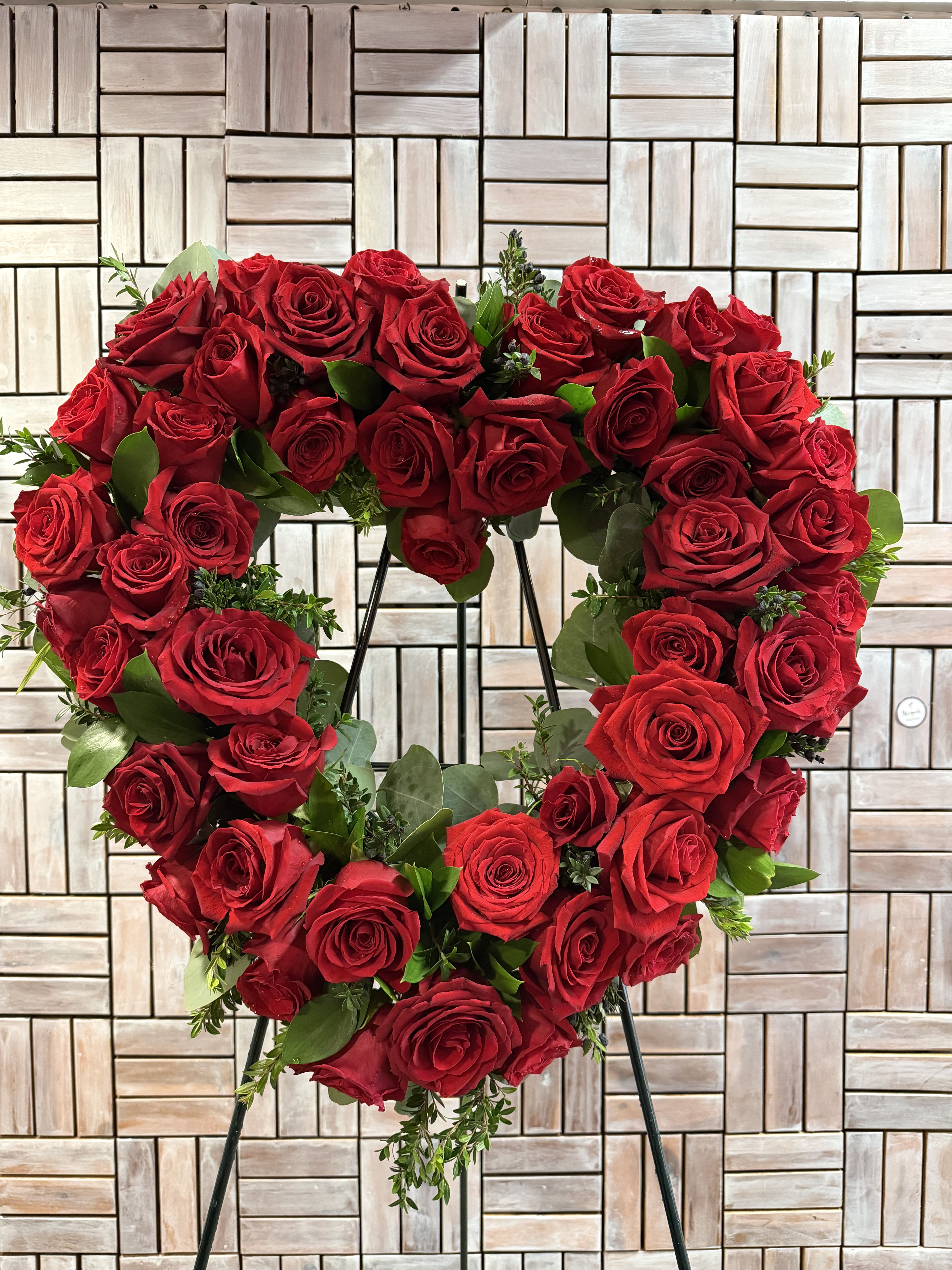 Heart-shaped wreath of red roses on a stand