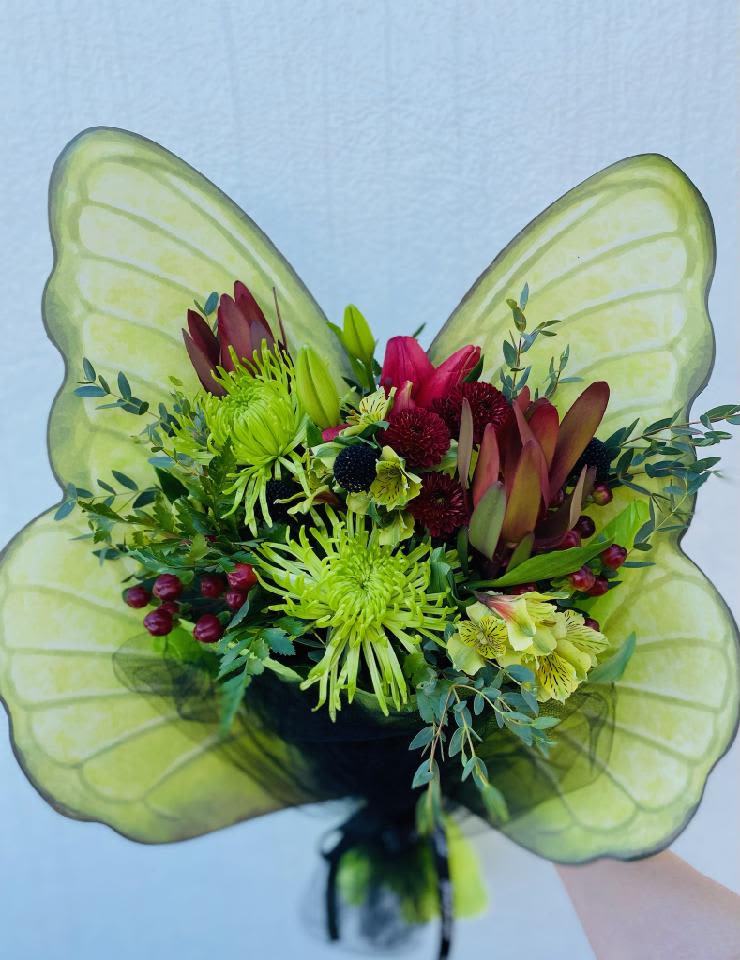 Bouquet with green and burgundy flowers in front of large translucent green wings