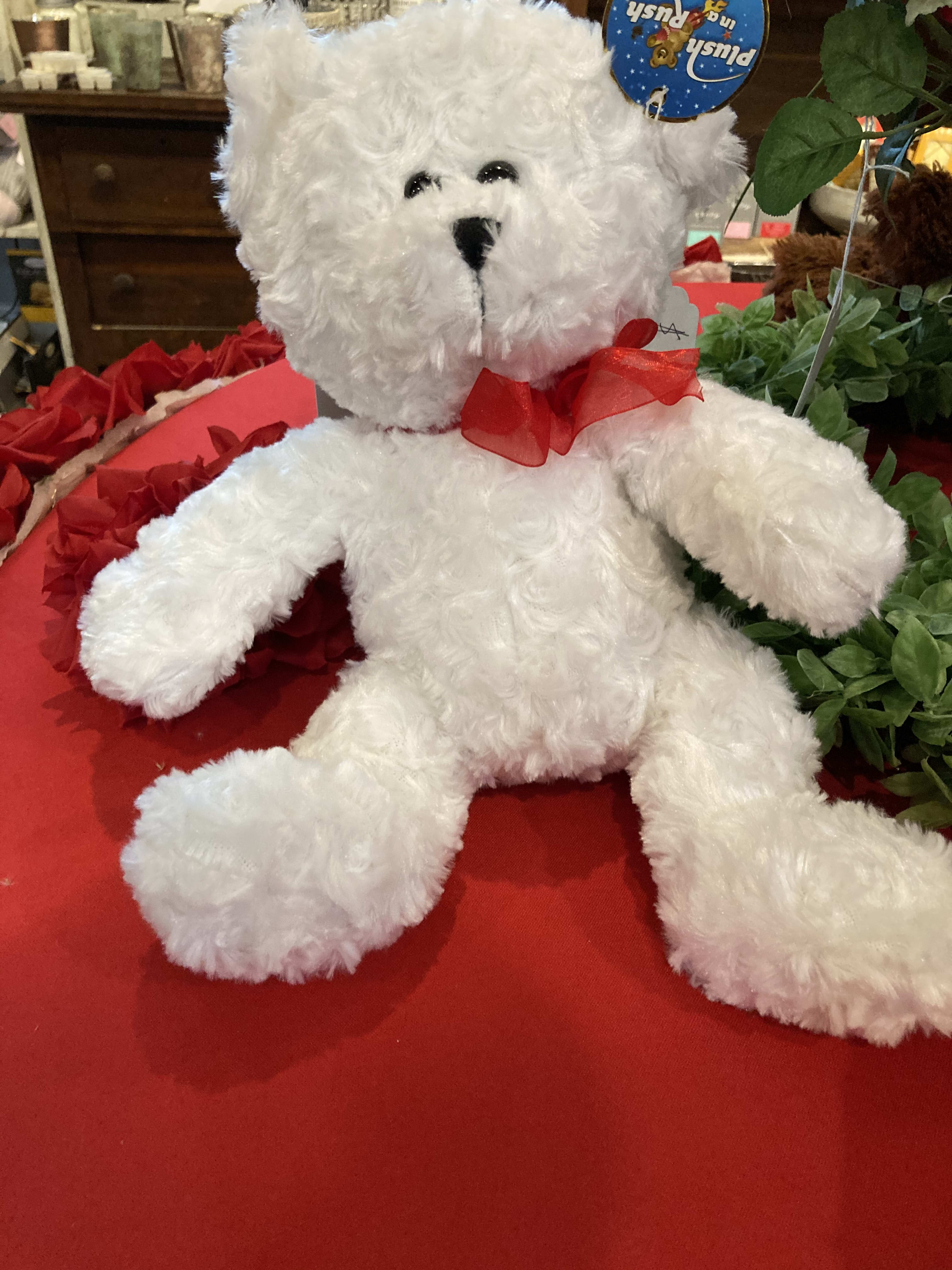 White plush teddy bear with a red ribbon bow