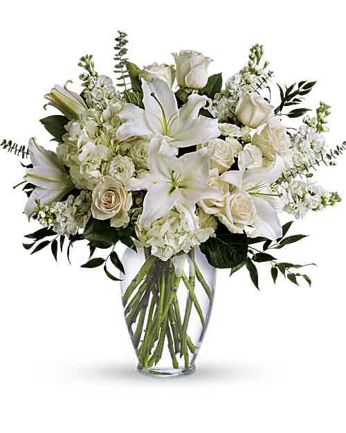 Dreams From the Heart Bouquet - A dreamy bouquet of white sympathy flowers is a comforting reminder of your love. The lush arrangement of soft colors is delivered in a majestic, tall glass vase. This gorgeous bouquet overflows with white hydrangea, crème roses, white spray roses, white oriental lilies, white stock, spiral eucalyptus, salal and Italian ruscus in a classic glass vase.