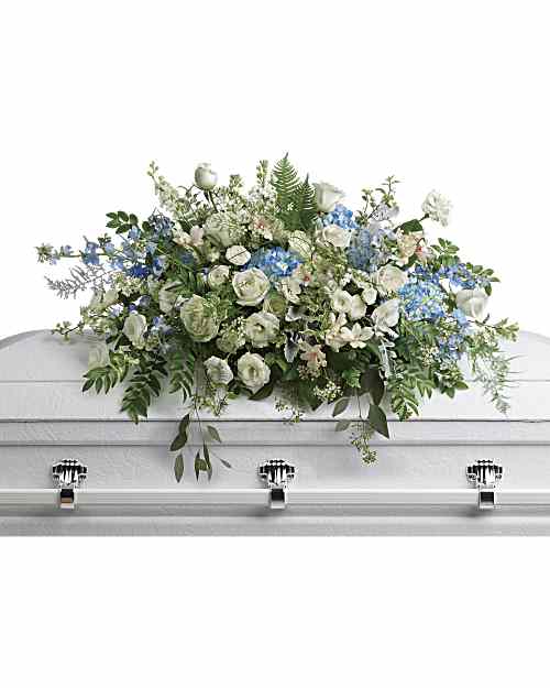 Tender Remembrance Casket Spray - Like wisps of clouds in a bright blue sky, this breathtaking spray of hydrangea, roses and alstroemeria refreshes and inspires. A beautiful way to remember your loved one. This stunning spray includes blue hydrangea, white roses, white spray roses, white alstroemeria, white lisianthus, blue delphinium, white larkspur, white stock, white waxflower, dusty miller, huckleberry, asparagus plumosus, pitta negra, lily grass, dagger fern, and lemon leaf.