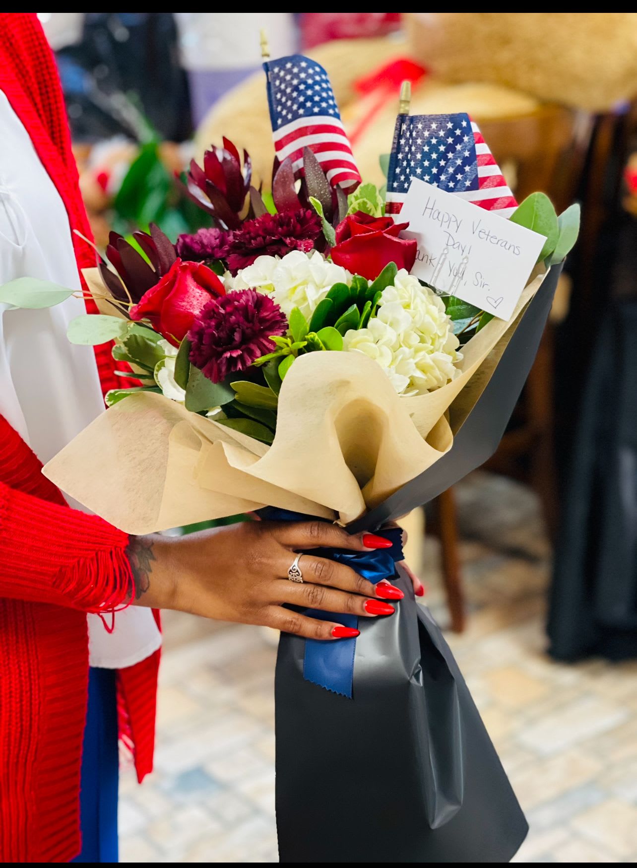 Bouquet of red roses, white hydrangeas, and burgundy flowers with small U.S. flags