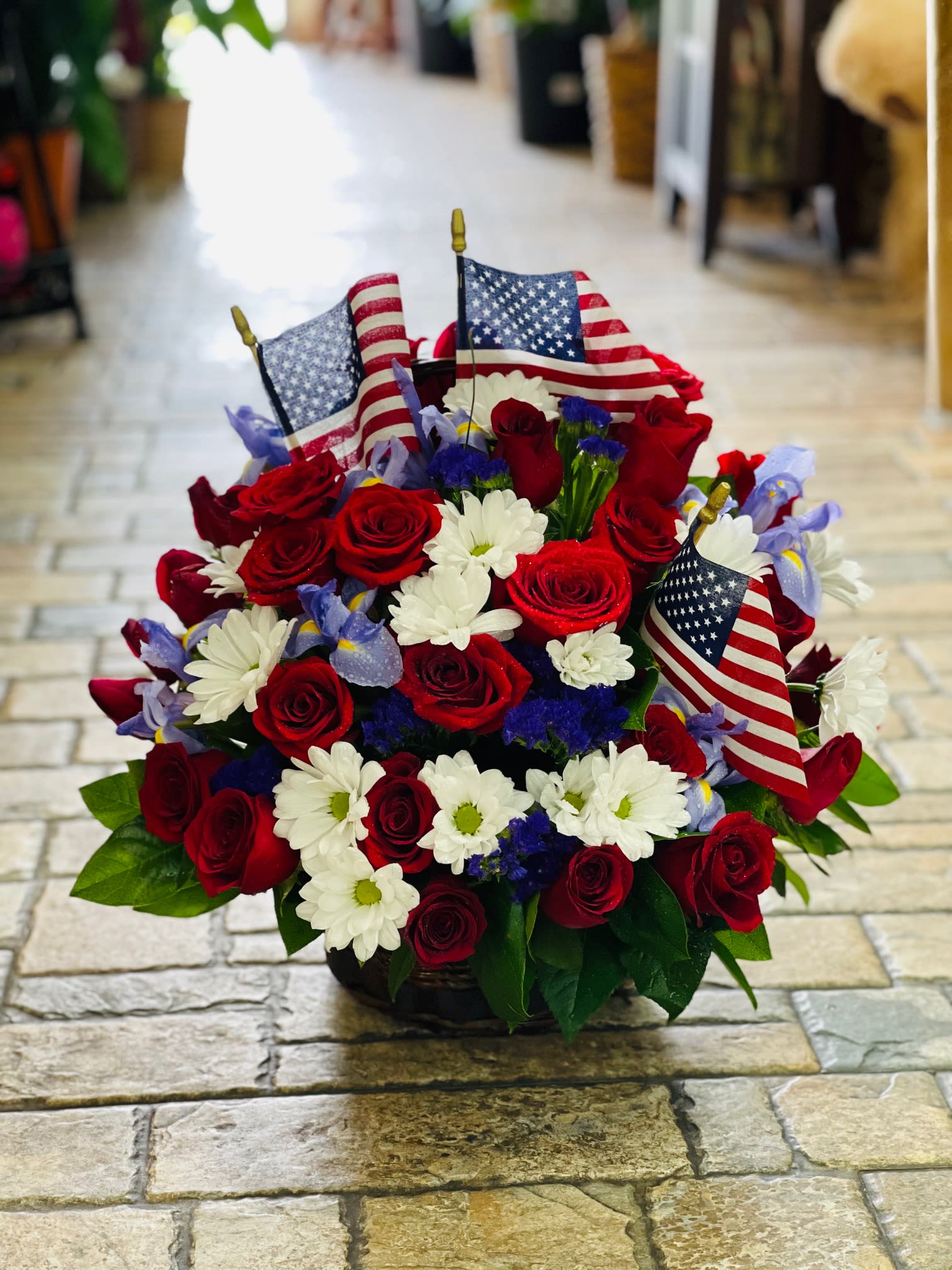 Red roses and white daisies arranged with small American flags