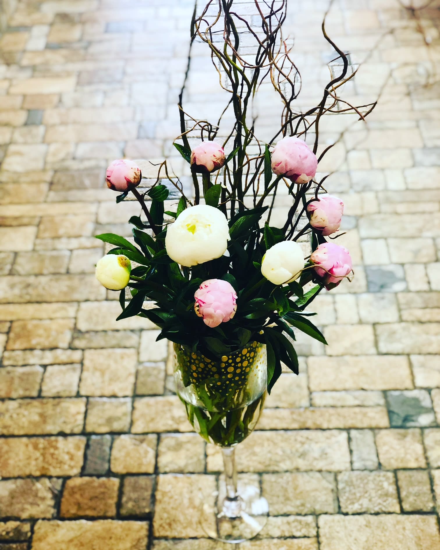 Pink and white peonies in a wine glass vase