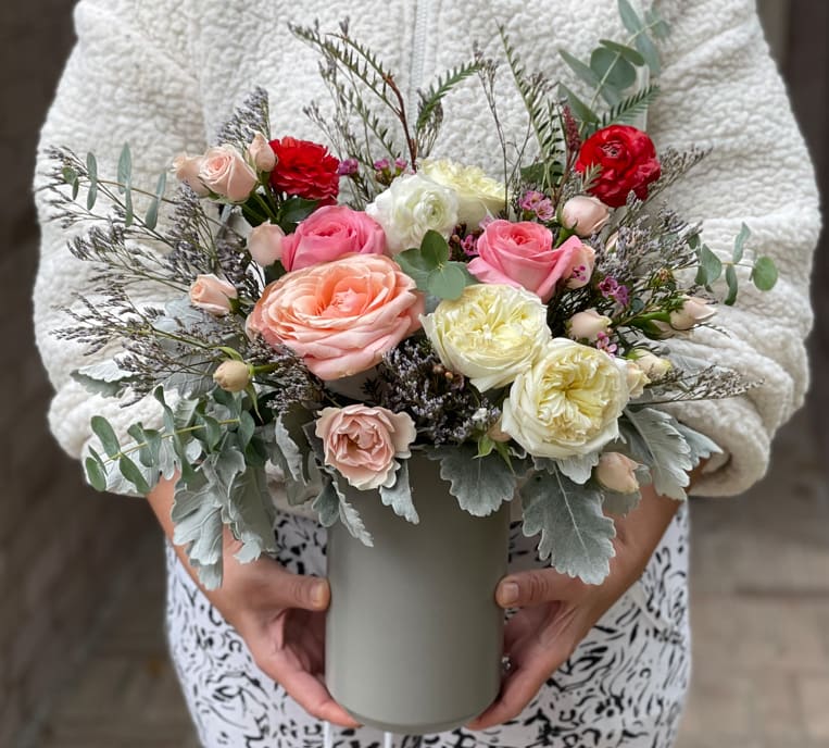 Mixed pink, peach, white, and red roses in a gray vase