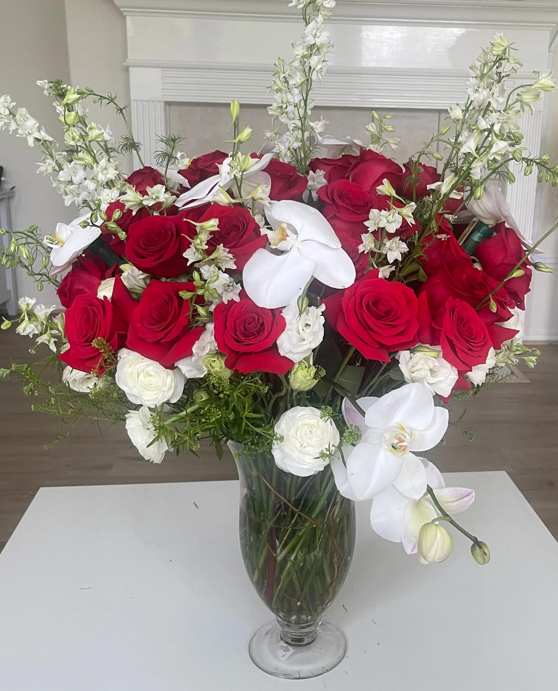 Red roses and white orchids arranged in a clear glass vase
