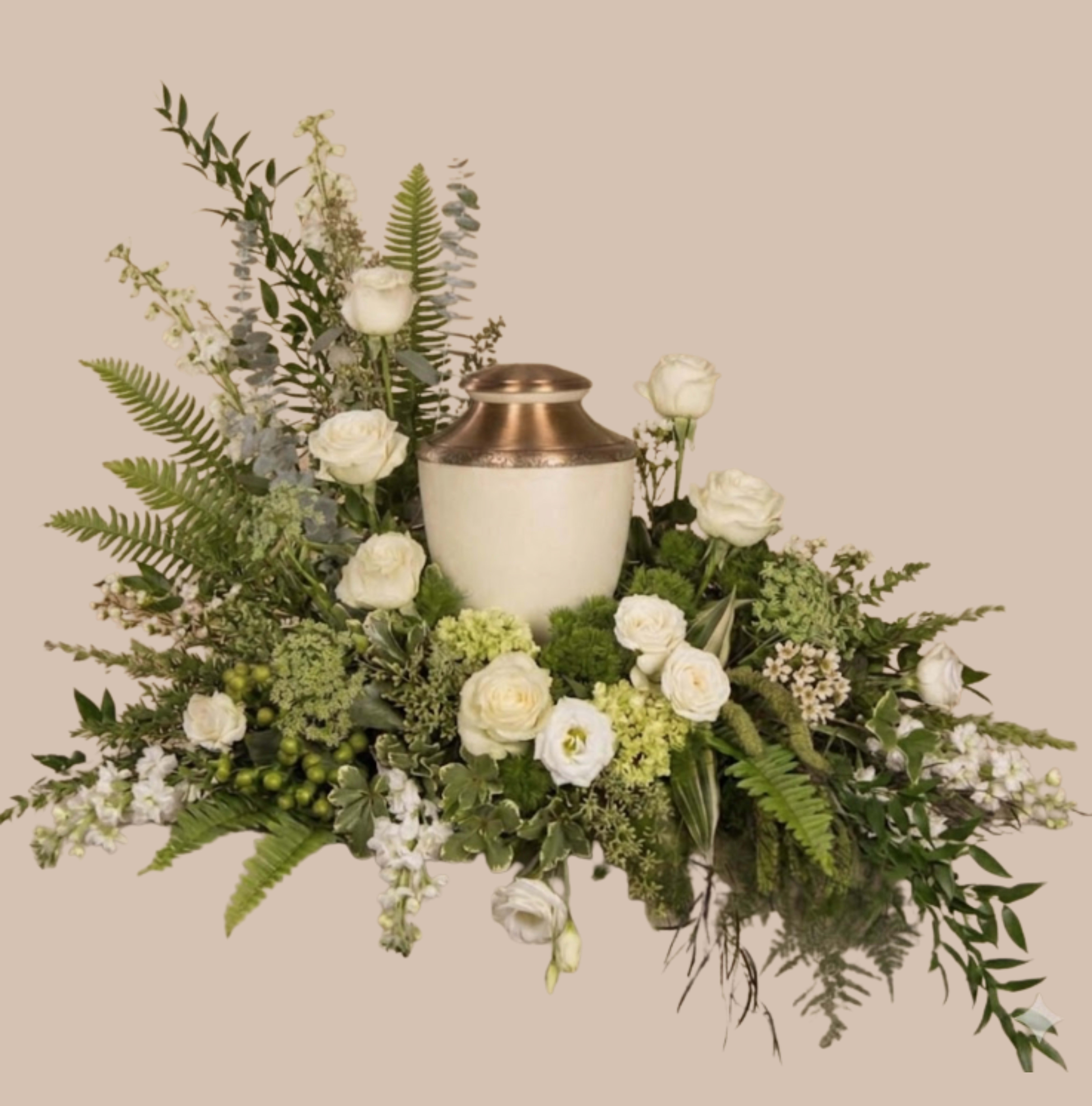 Emerald Oasis Tribute - A low, expansive spray of white blooms arranged around a cream ceramic urn creates a serene focal point that honors a thoughtful moment - ideal as a sympathy arrangement, memorial tribute, or quiet wedding centerpiece. The White Meadow Tribute blends white roses and lisianthus with airy filler flowers and mixed greenery to convey calm, respect, and gentle beauty for the person you're remembering or celebrating.  Set in a substantial cream urn with a copper-toned rim, the design spreads wide with a soft, asymmetrical silhouette: a restrained, formal presentation at the center with taller accents and fern-like foliage flowing outward. Textures range from the velvety rose petals to the delicate lisianthus and fine, feathery greenery, delivering a natural meadow feel in a controlled, elegant shape.  This arrangement suits display on a mantel, chapel table, or reception space where a lasting, composed statement is needed - the kind of floral tribute that helps someone feel seen and honored. The low, balanced profile makes placement easy; for care, keep water fresh and the stems trimmed so the blooms stay graceful throughout the services or event.