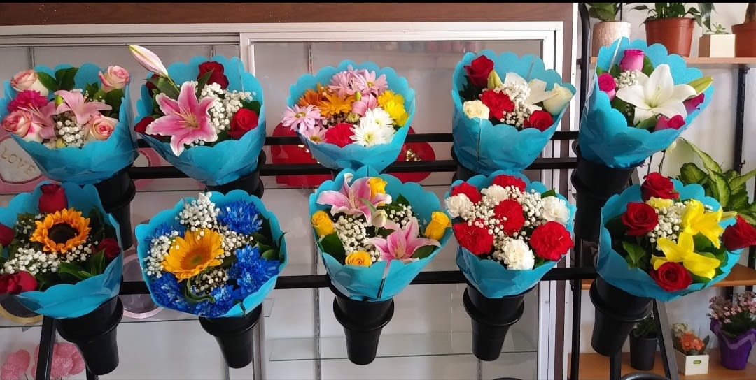 Assorted bouquets wrapped in bright blue paper on black stands