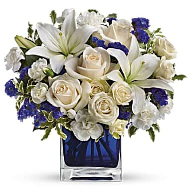 White lilies and roses in a blue glass vase with purple accents