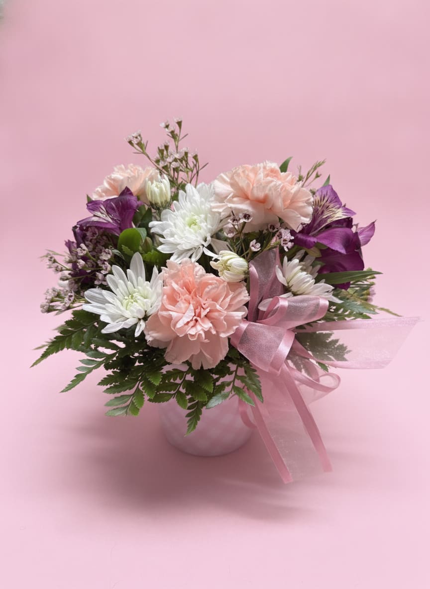 Hello, Baby Girl! - Hello Baby Girl is a sweet and cheerful floral arrangement designed in a pink plaid keepsake container, perfect for welcoming a precious new arrival. Soft white cushion mums, gentle purple alstroemeria, blush pink carnations, and airy pink waxflower create a delicate, feminine palette full of warmth and joy.  Finished with a pink ribbon detail, this design is a simple, heartfelt celebration of a beautiful baby girl.   All flowers, floral colors, and containers are subject to change due to availability.
