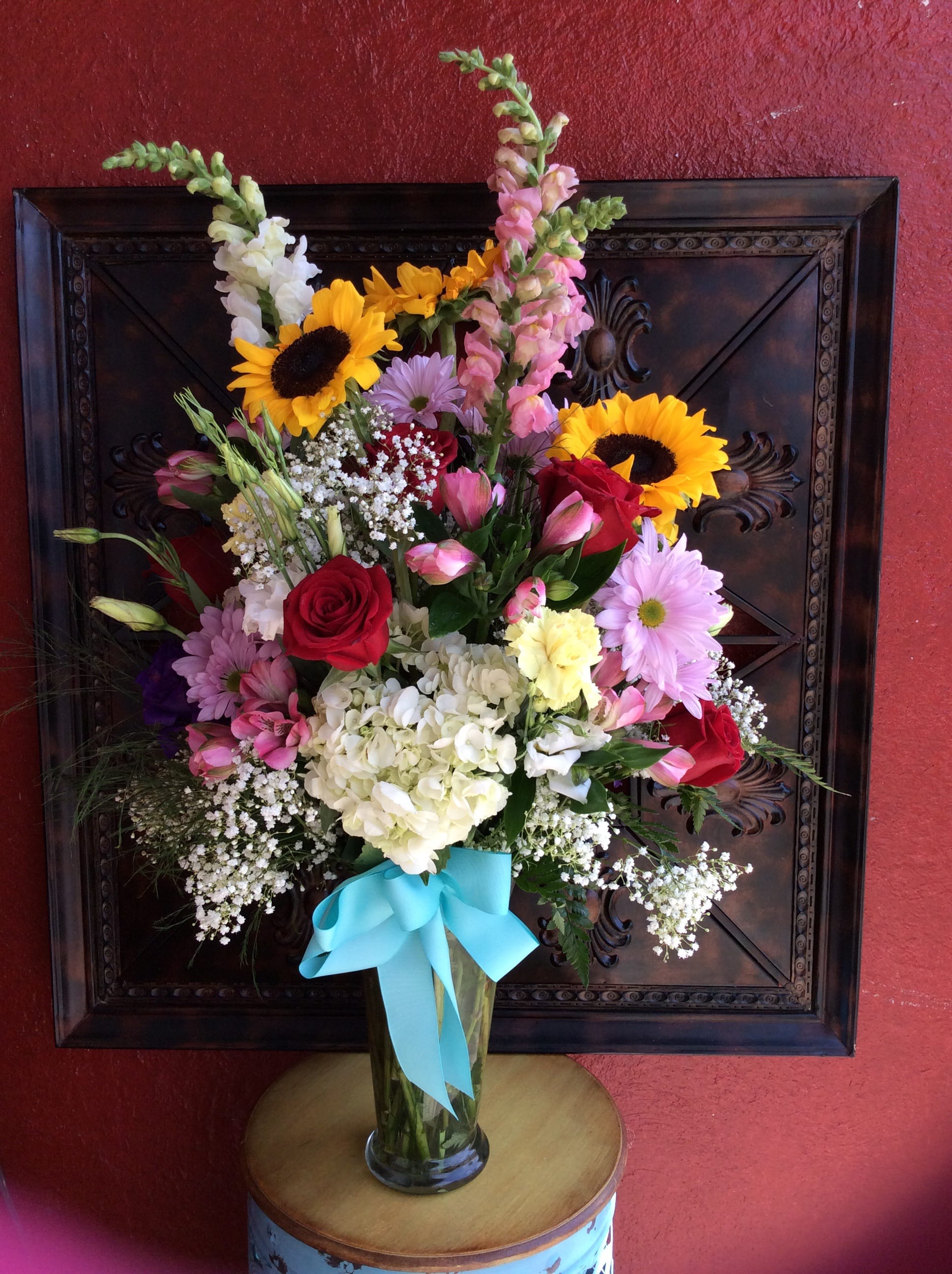 Mixed bouquet in a glass vase with sunflowers, roses, and daisies