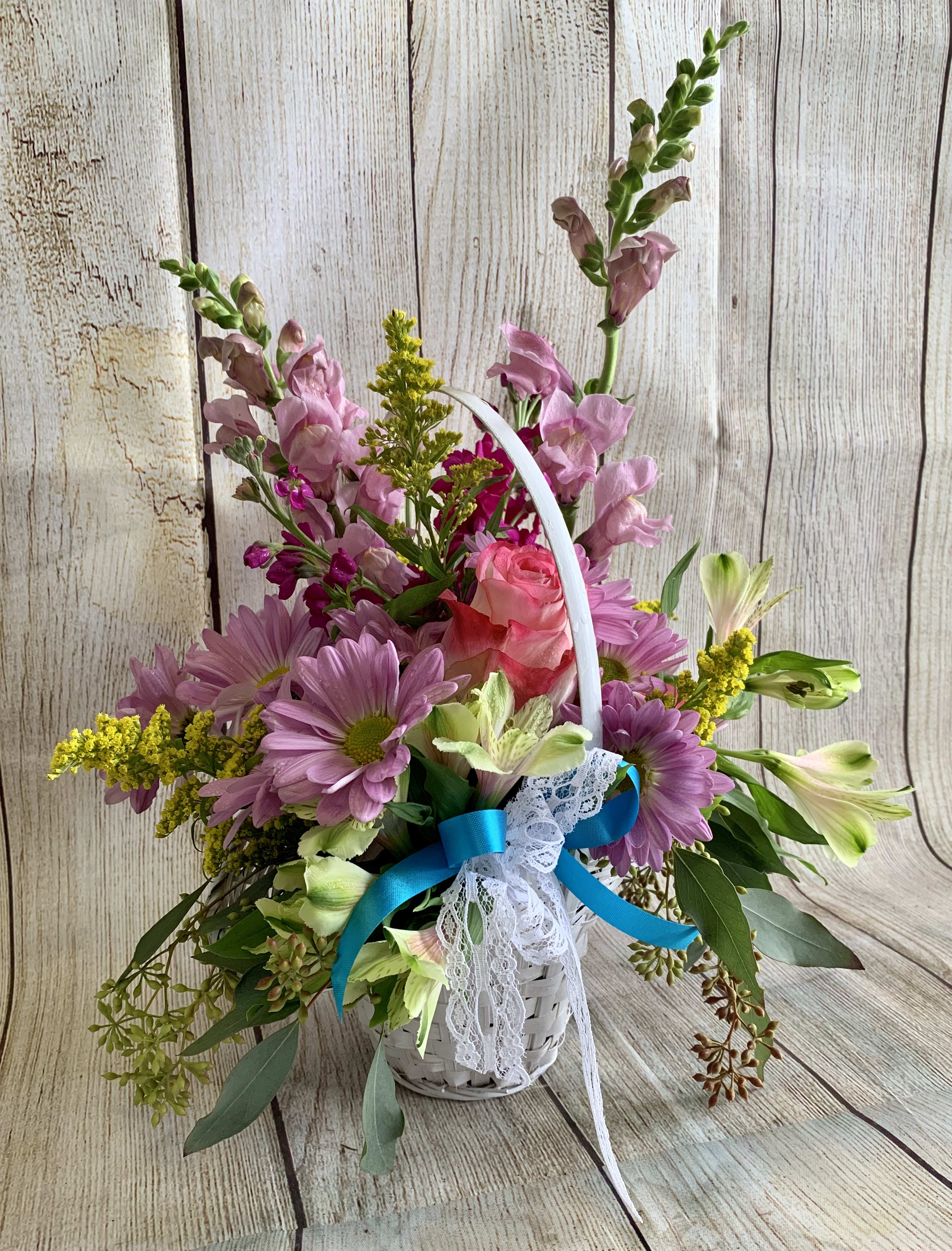 Basket arrangement of pink and purple flowers with a blue ribbon