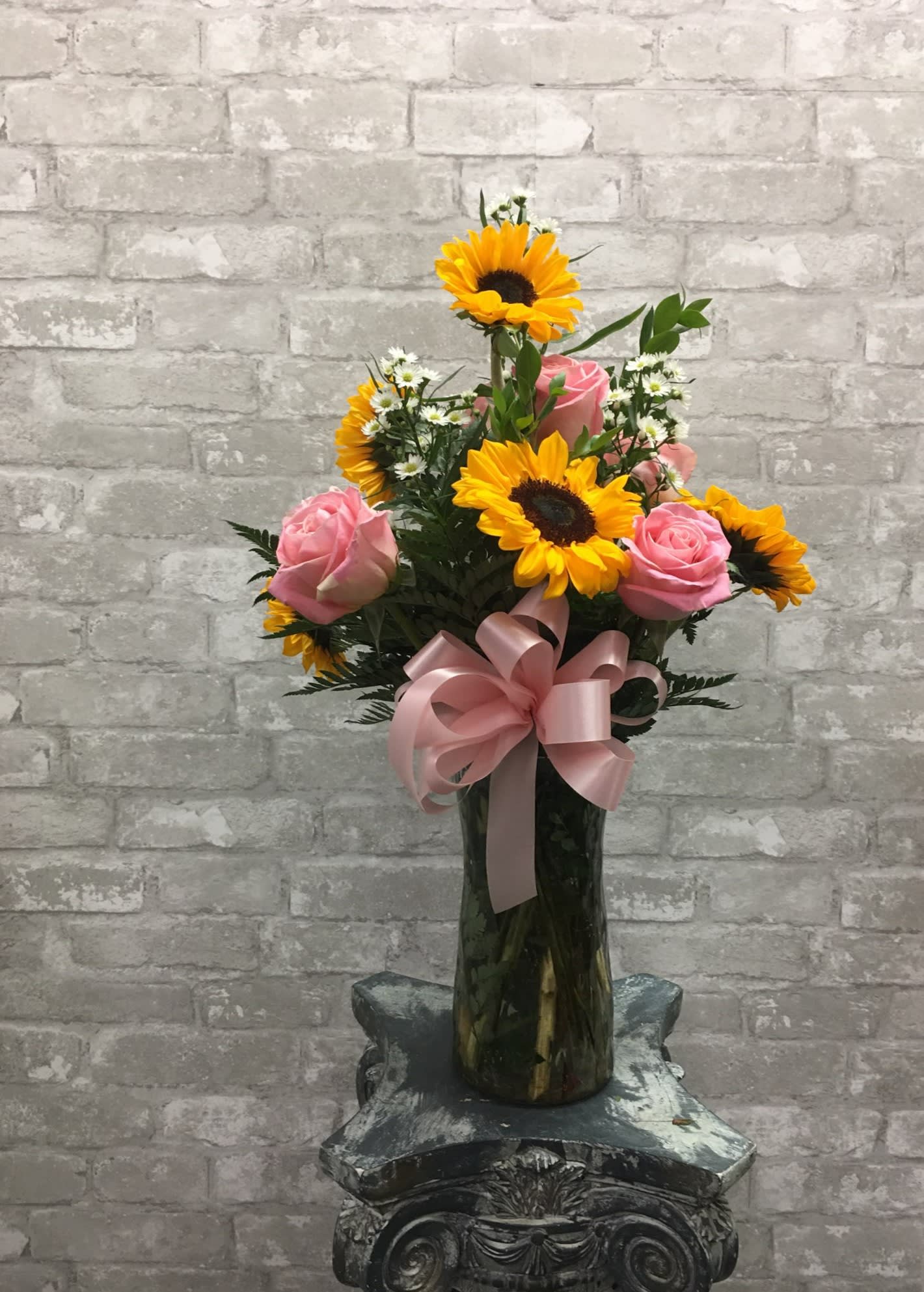 Sweet Sunshine FG - This showy arrangement features six sunflowers and six colored  roses in a tall clear vase.  Roses may be any color MIGHT Not be Pink  Deluxe -- includes premium foliage. Premium -- includes premium foliage and premium accent flowers.