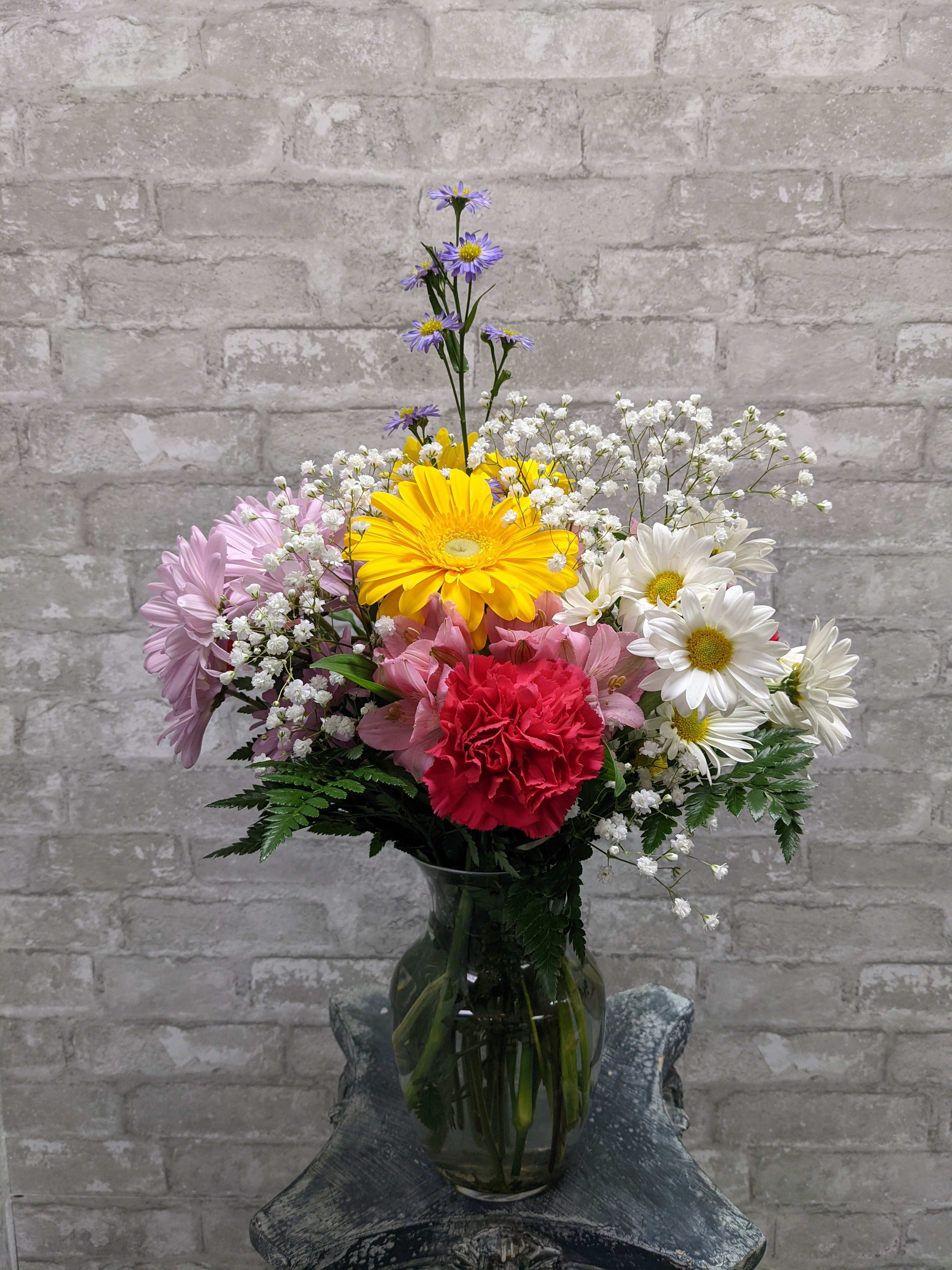 Mixed bouquet of daisies, carnations, and baby's breath in a glass vase