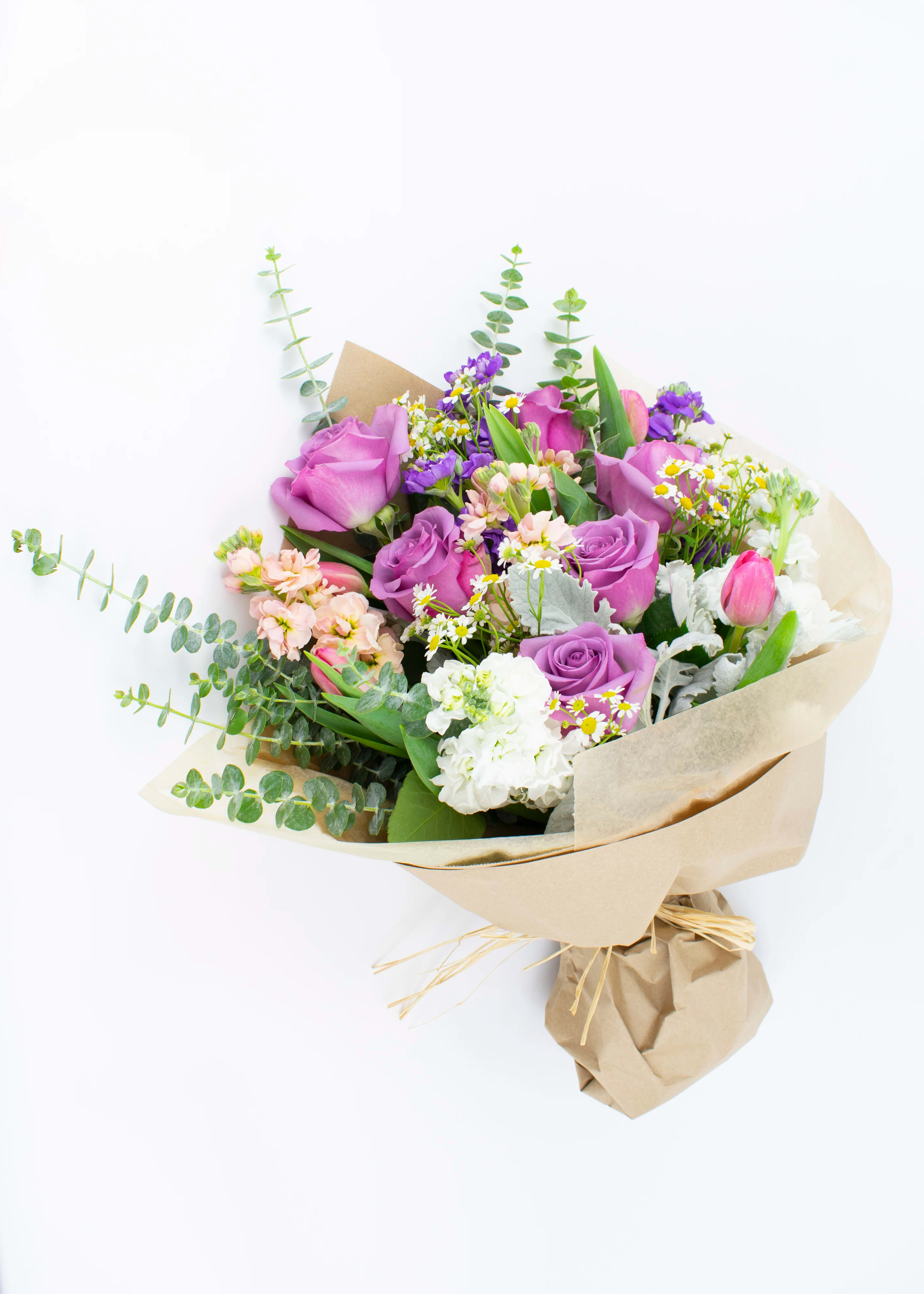 Bouquet of purple roses and mixed small flowers wrapped in kraft paper