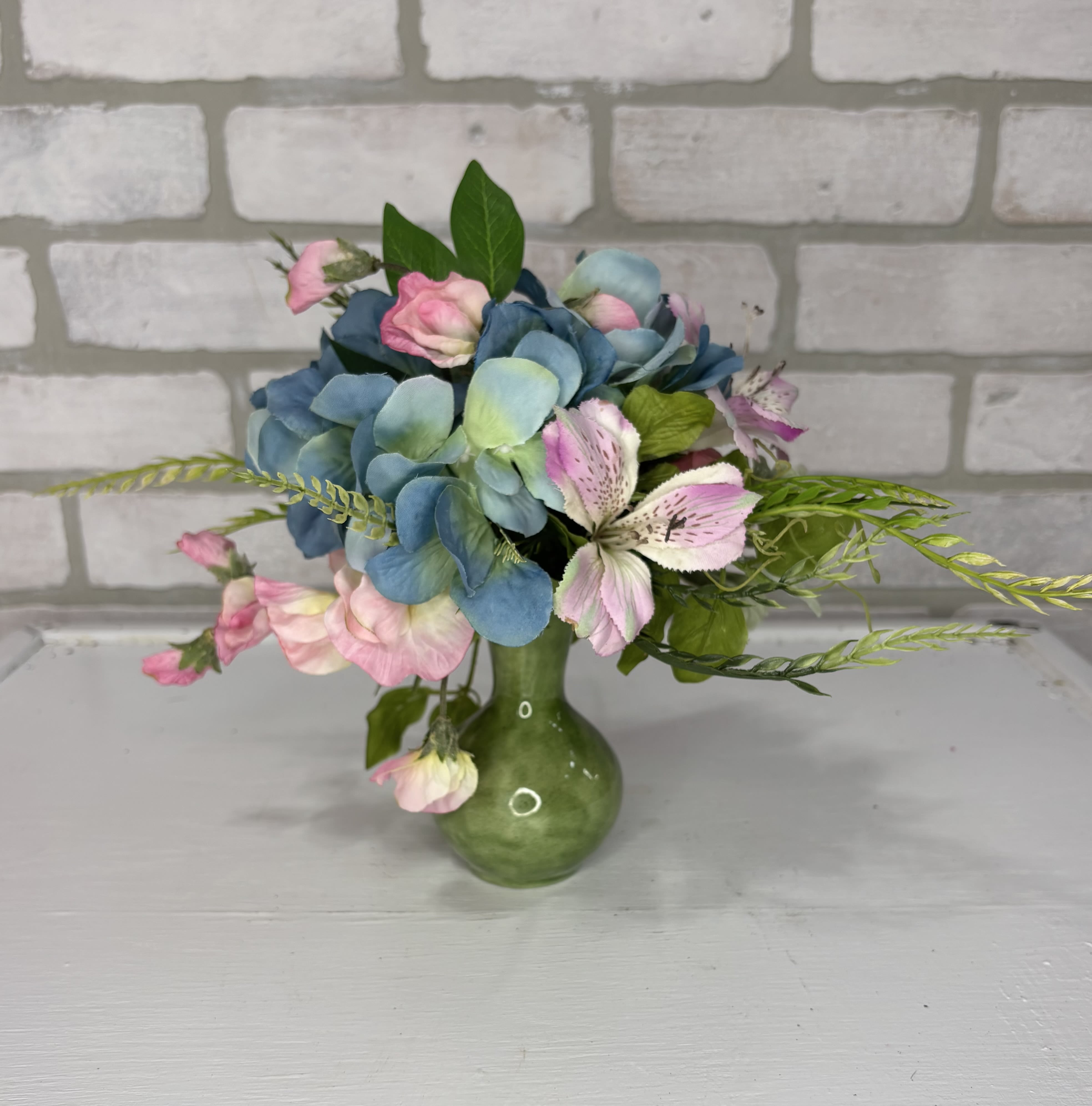 Blue hydrangeas and pink flowers in a green vase