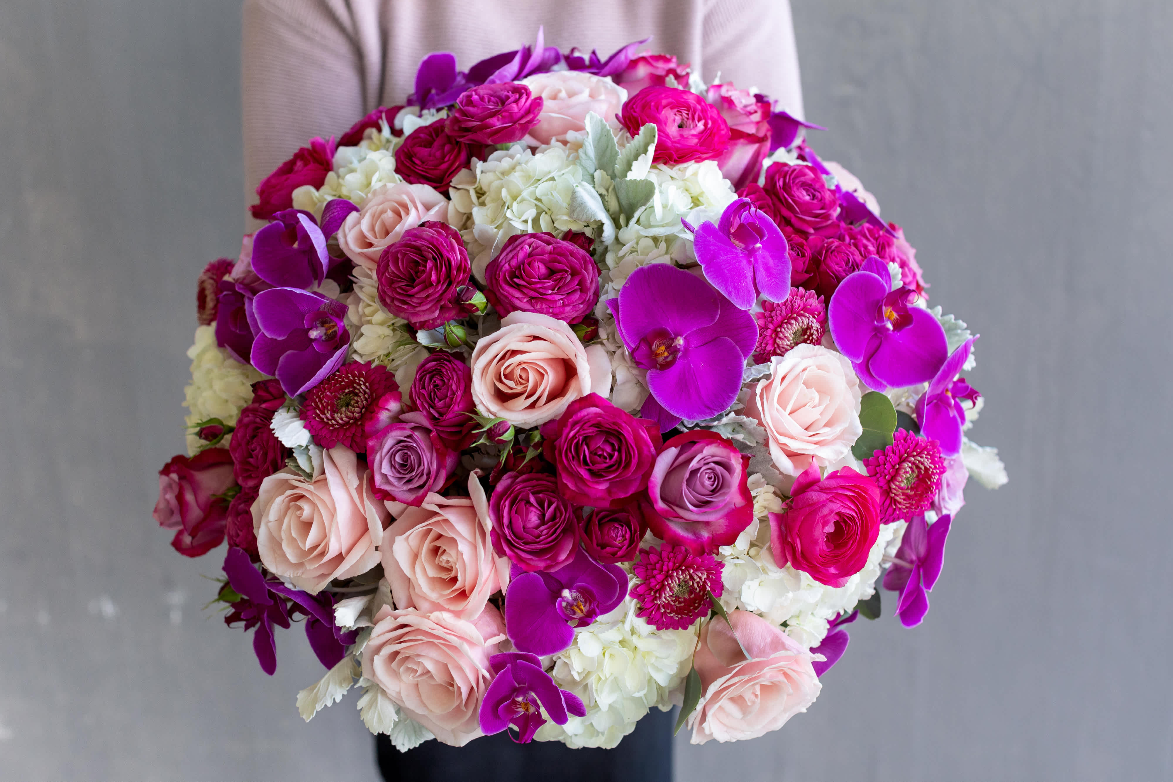 Round bouquet of pink roses, white hydrangeas, and purple orchids