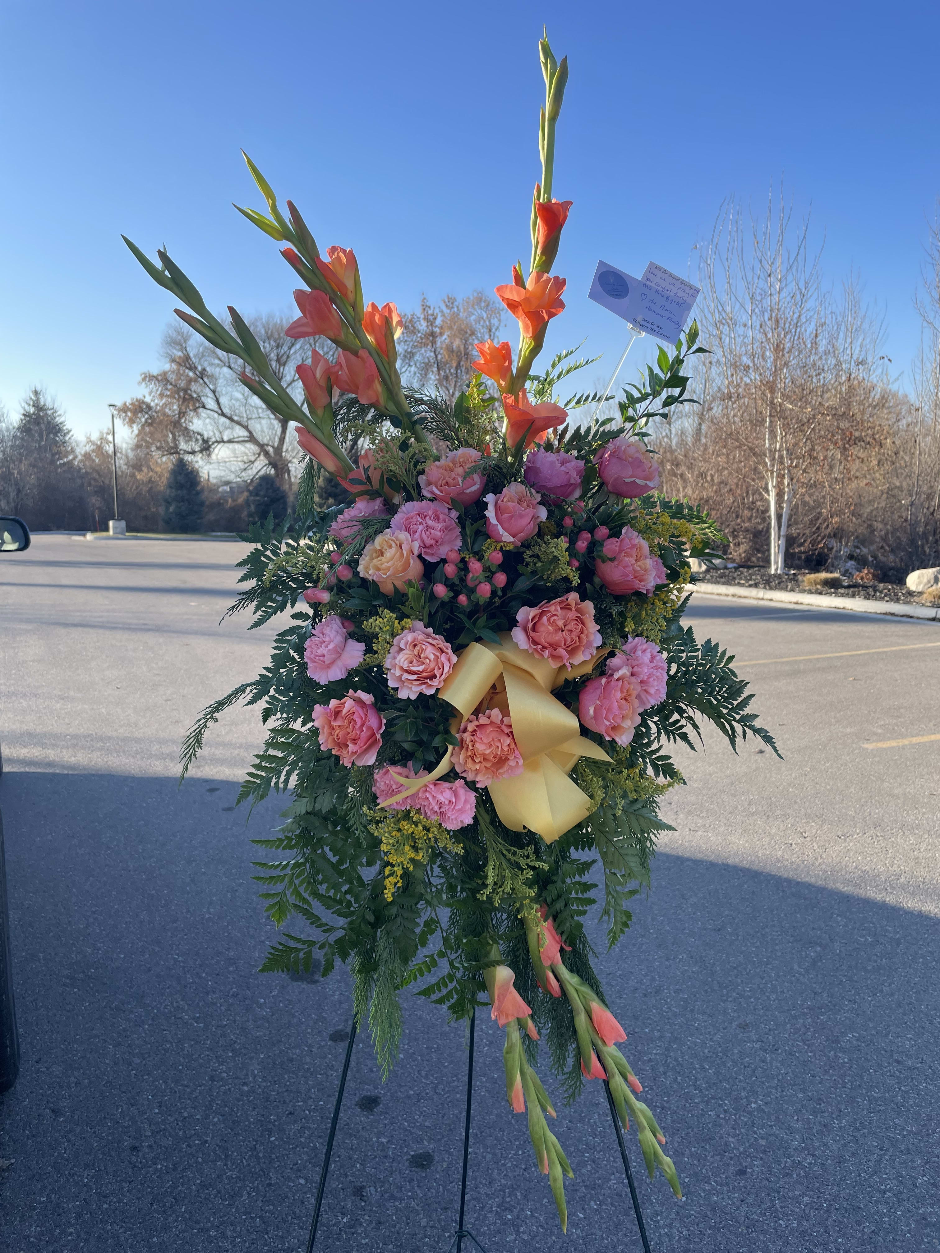Standing floral spray with pink roses and orange gladiolus on an easel