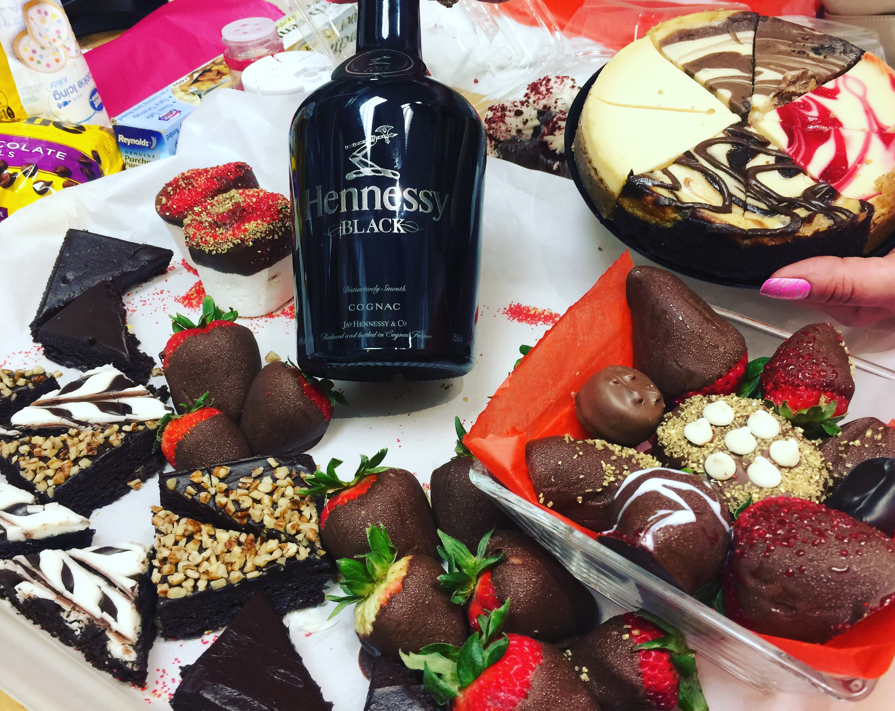 Assorted chocolate-covered strawberries and desserts around a Hennessy Black bottle