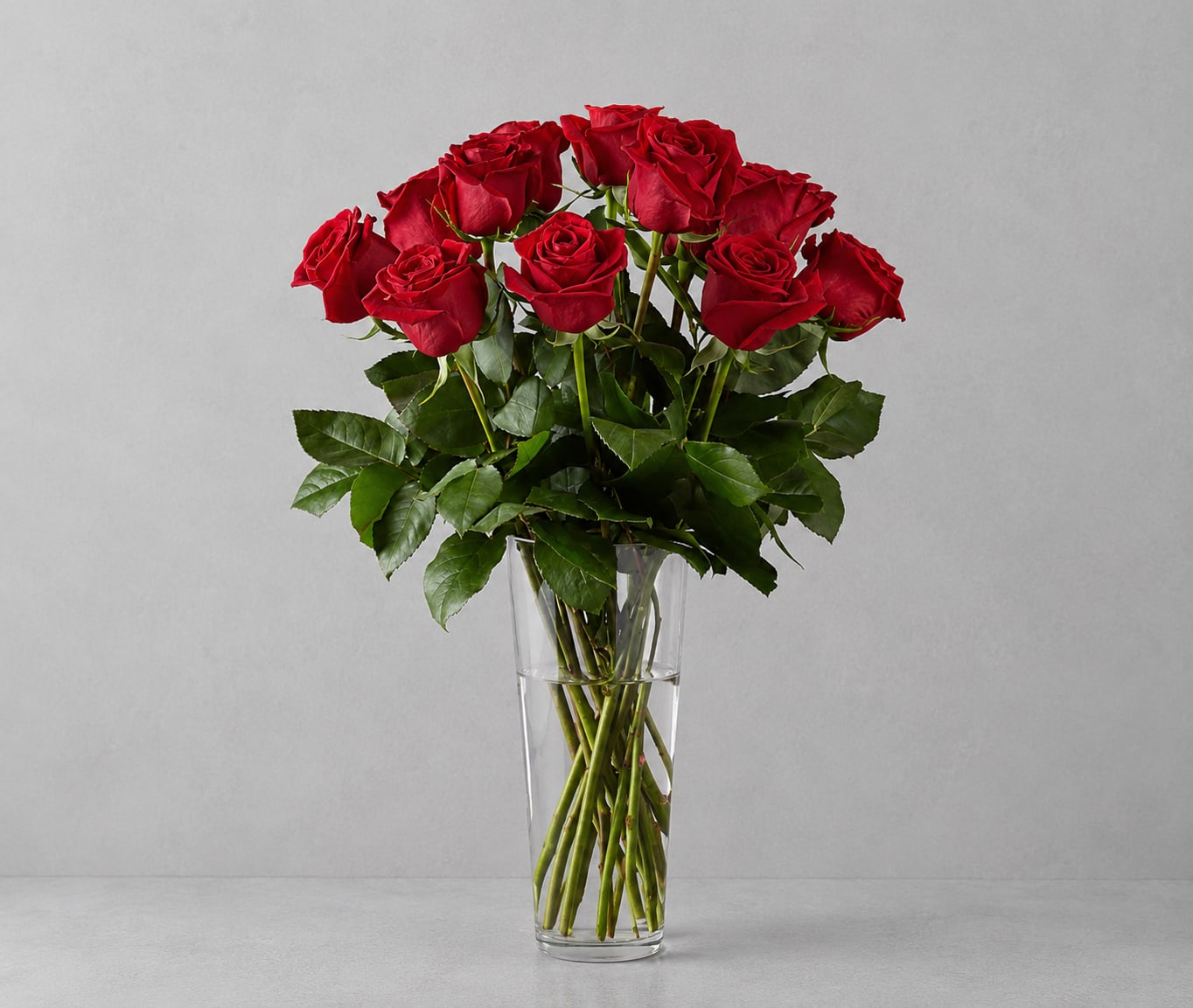 Red Roses  - A stunning bouquet of half dozen vibrant red roses, elegantly arranged with filler of choice, captures the essence of love and passion. Nestled amongst floral greens, the timeless beauty of the roses is accentuated, creating a romantic and enchanting display. A finishing touch of a red vase adds a touch of sophistication, making this bouquet a perfect expression of heartfelt emotions.  
