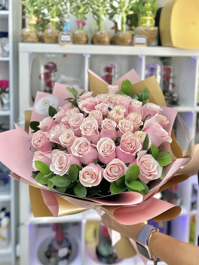 Large hand-tied bouquet of light pink roses wrapped in pink and tan paper