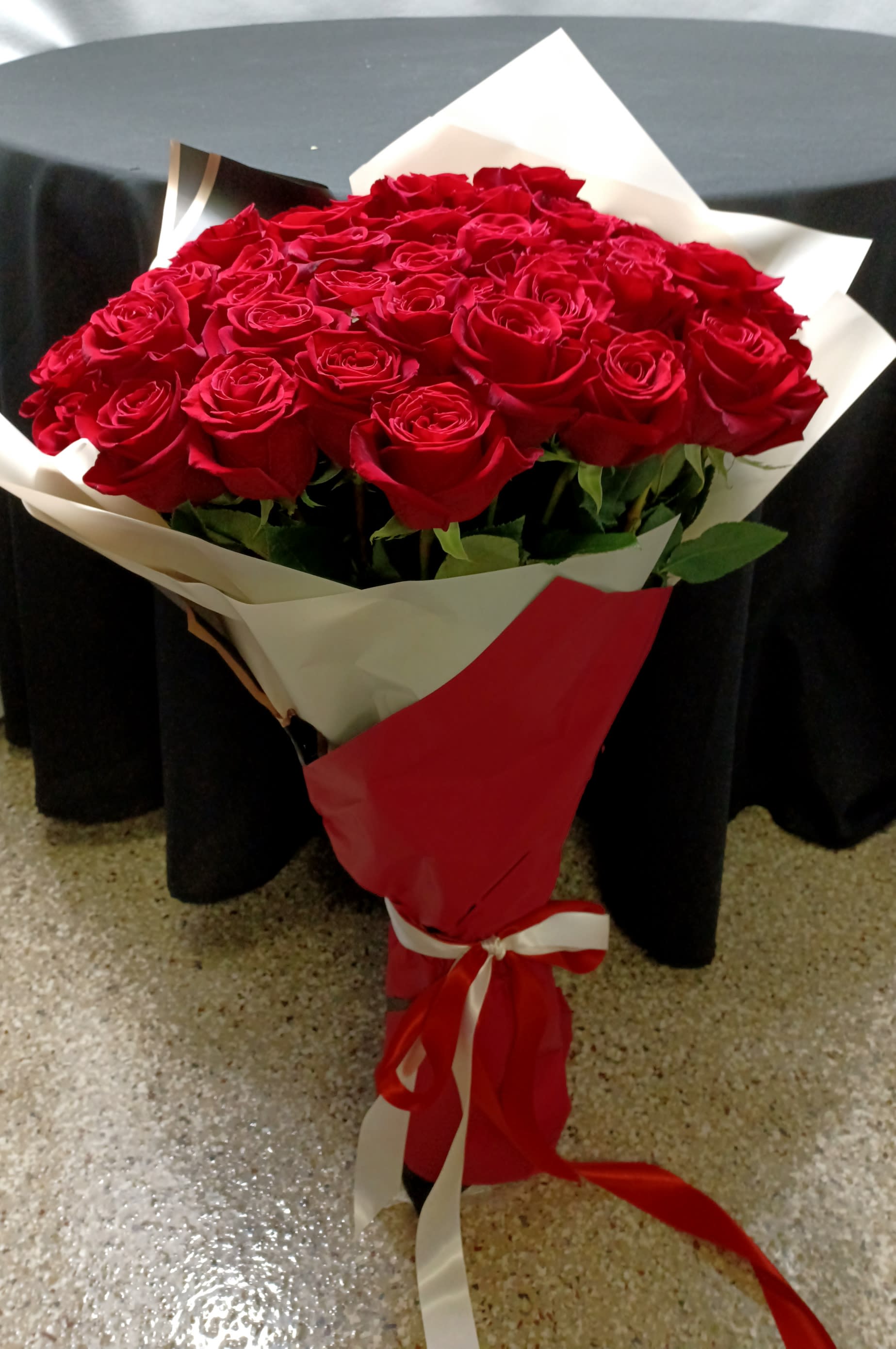 Bouquet of red roses wrapped in red and white paper with a ribbon