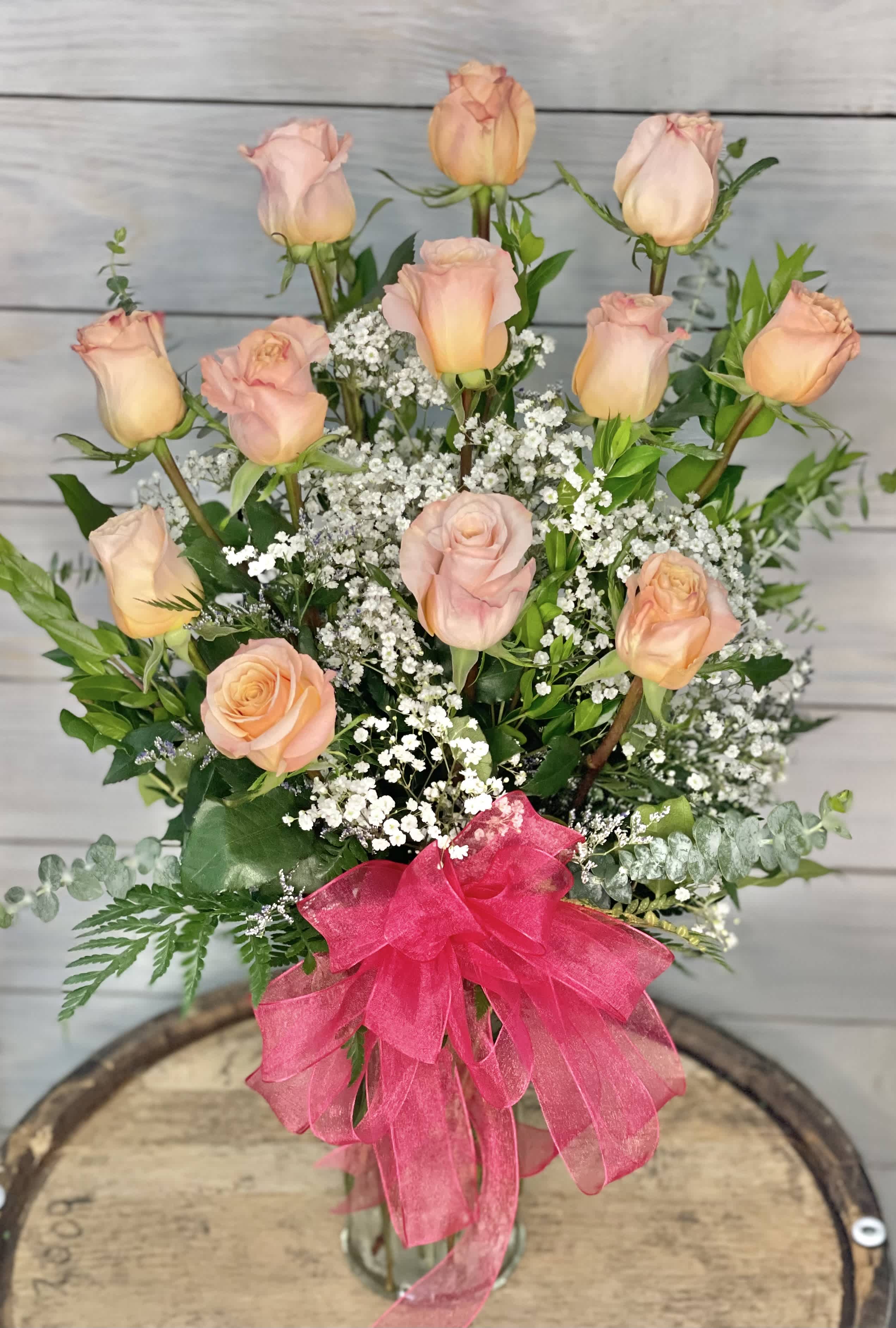Pink roses and peach roses arranged with baby's breath in a glass vase