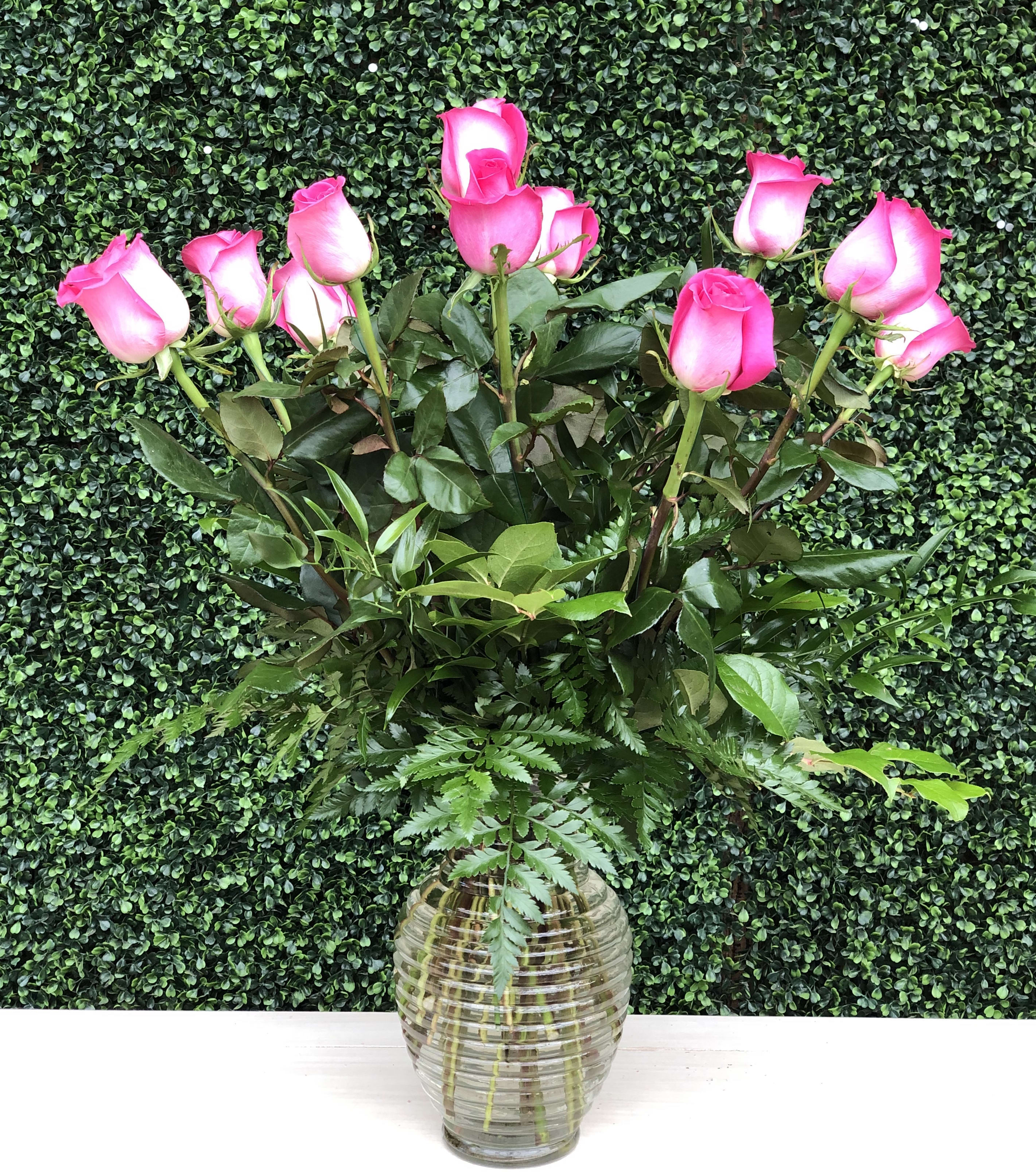 Pink roses in a clear glass vase with greenery