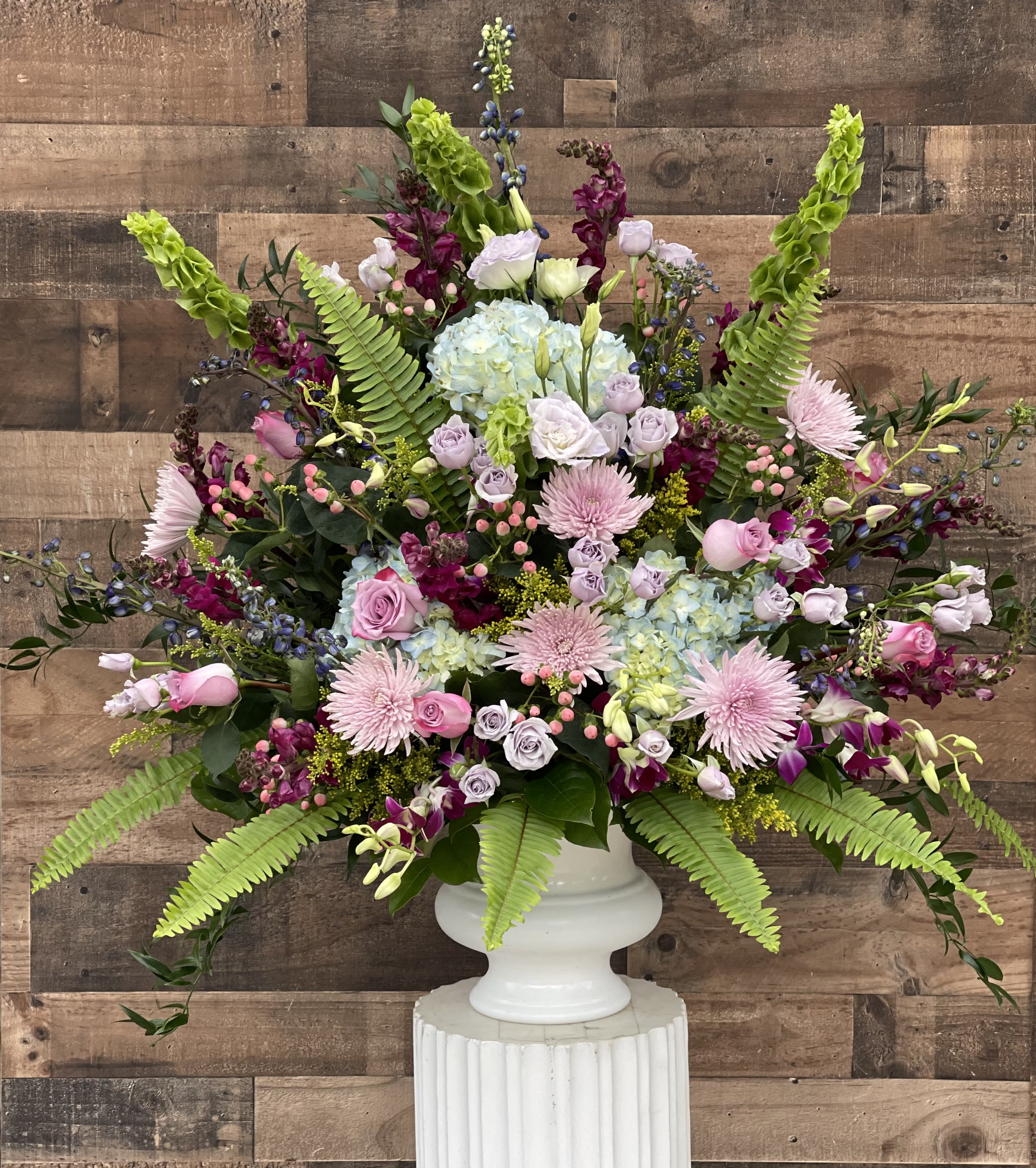 Large pastel floral arrangement in a white pedestal vase